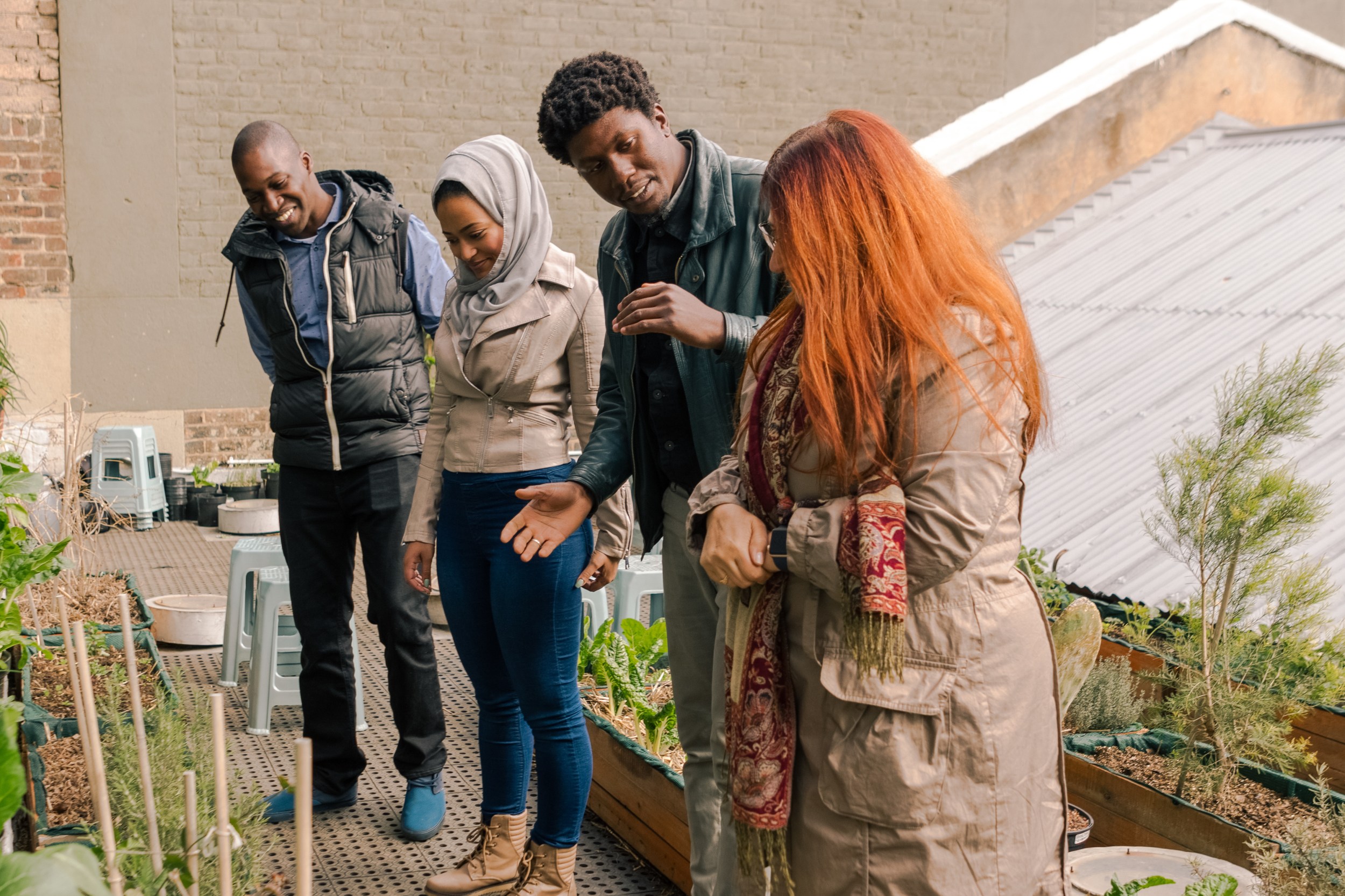 A diverse group of people talking while standing in front of a roof garden.