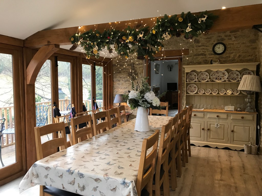 A country home dining room with holiday tinsel hanging from an exposed rafter over the table.
