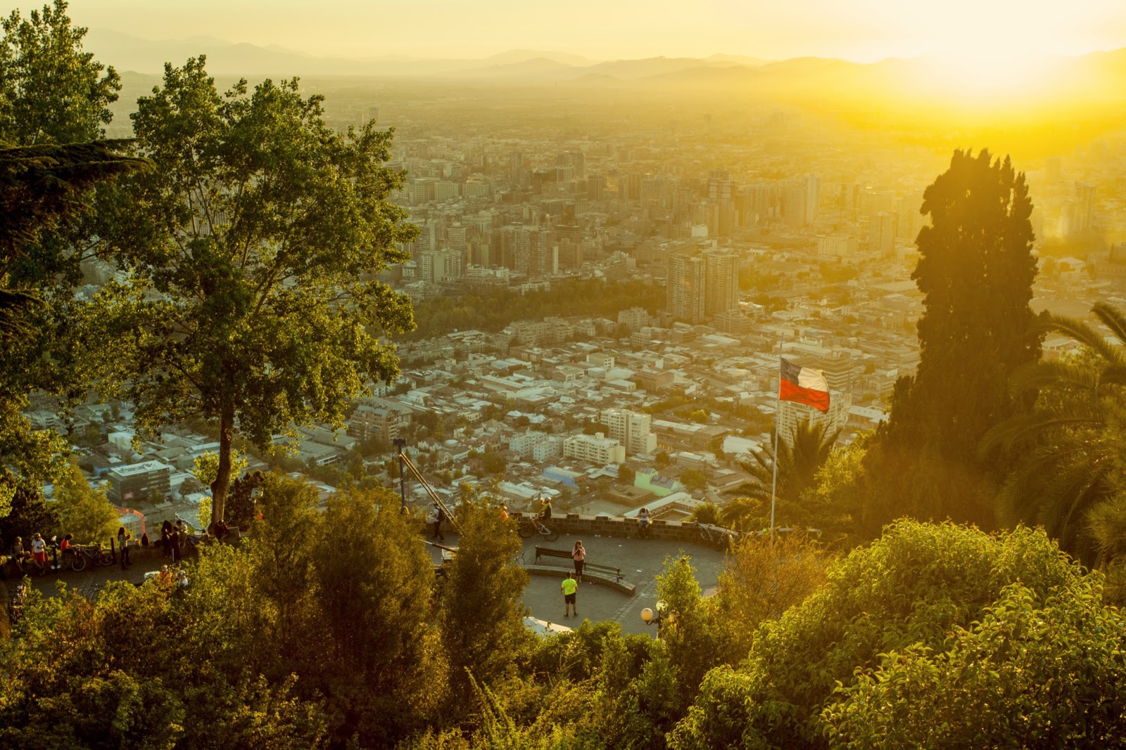 Panoramic view of Santiago de Chile during the sunset, with a flag of the country to the right
