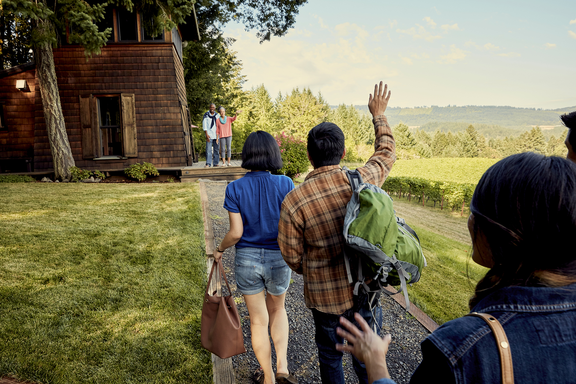 A group of friends are greeted by their hosts at their Airbnb listing.