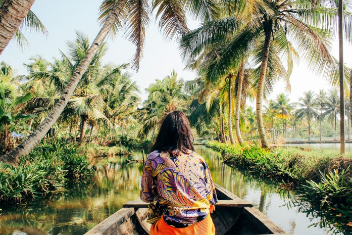 A young woman kayaks through the backwaters of Monroe Island in Kollam District, Kerala, South India.