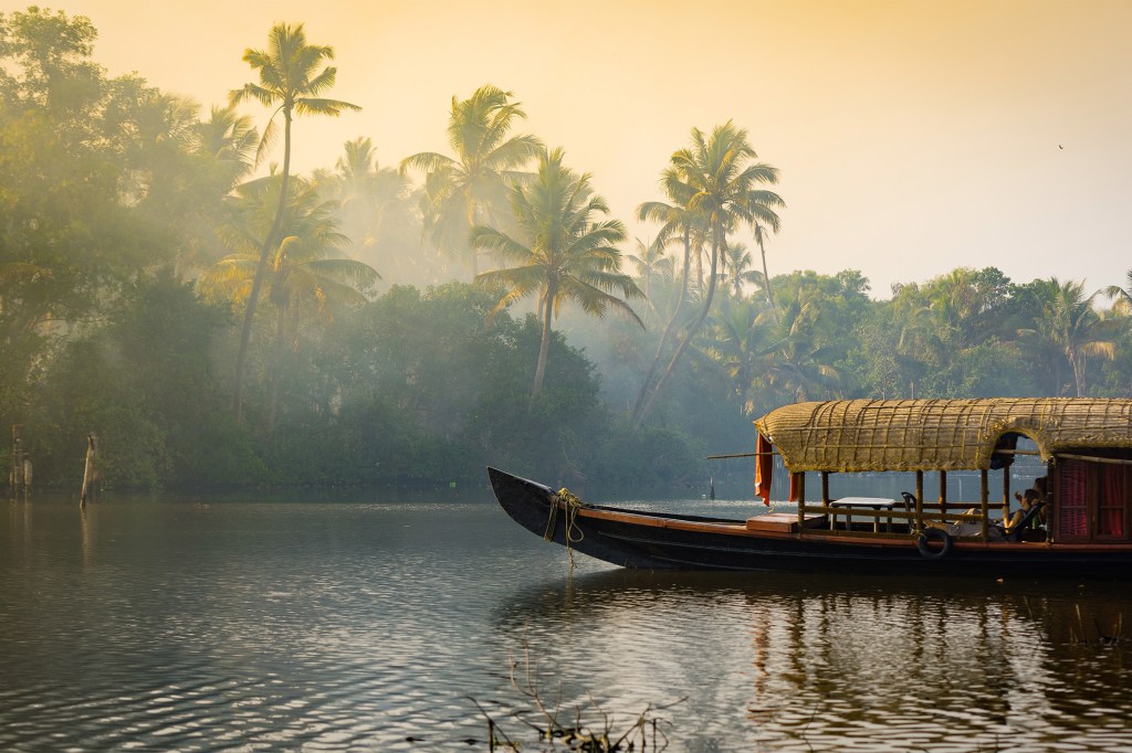 A traditional house boat is anchored on the shores of a fishing lake in Kerala's Backwaters, India.