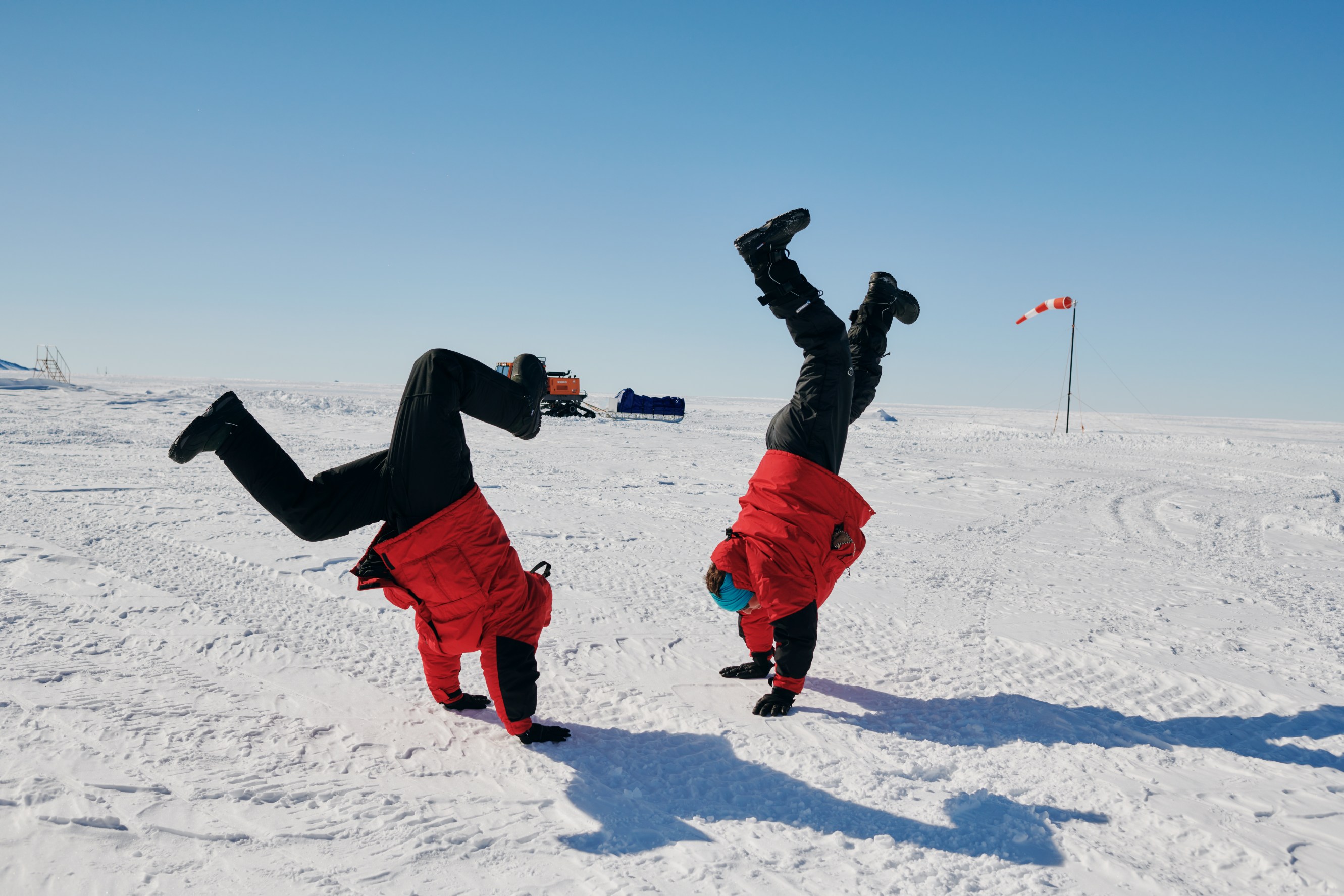 Antarctic Sabbatical volunteers pretend to hold up the world by doing handstands in Antarctica