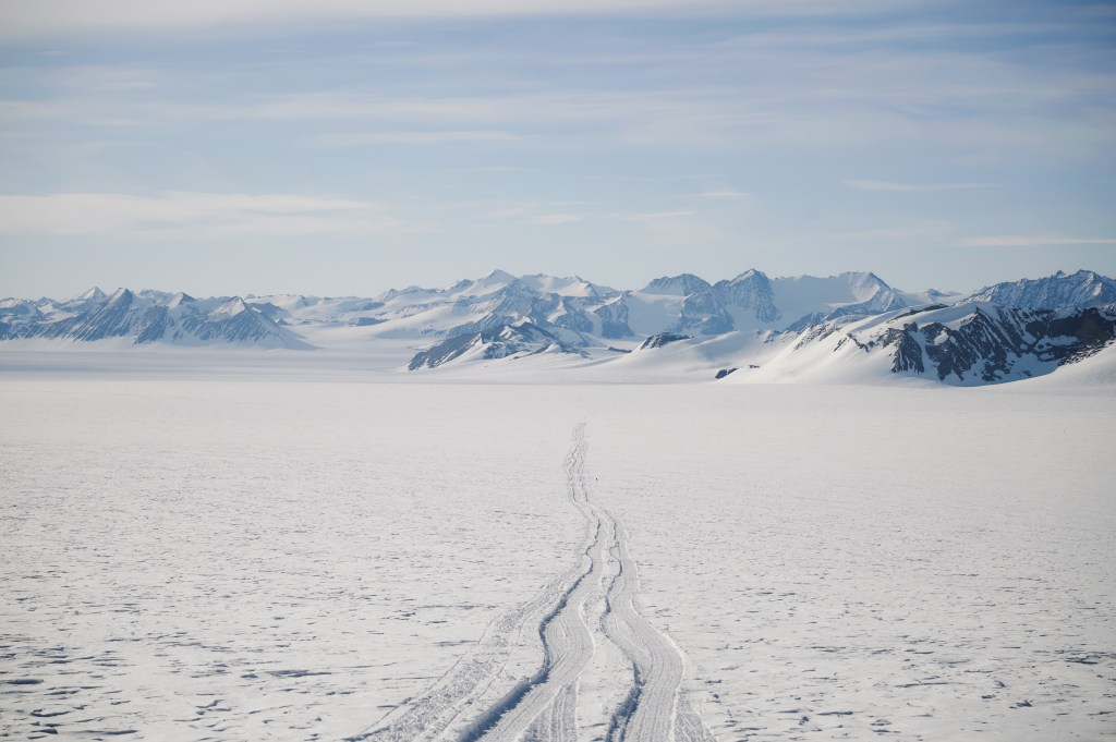 Tire tracks disappear into the distance on the awe-inspiring, frozen landscape of Antarctica