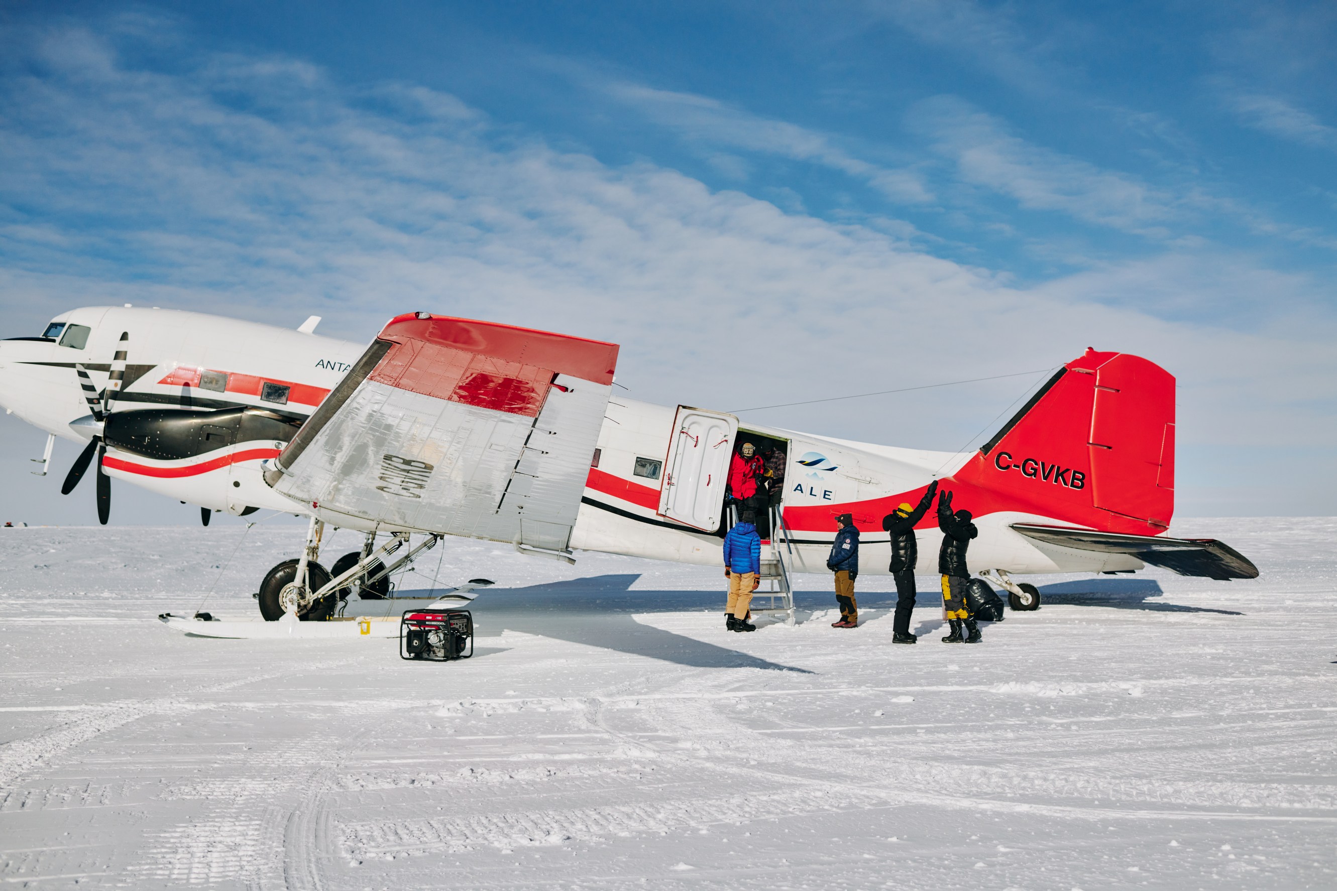 Citizen scientists high five outside the Basler plane that is used to fly to the South Pole