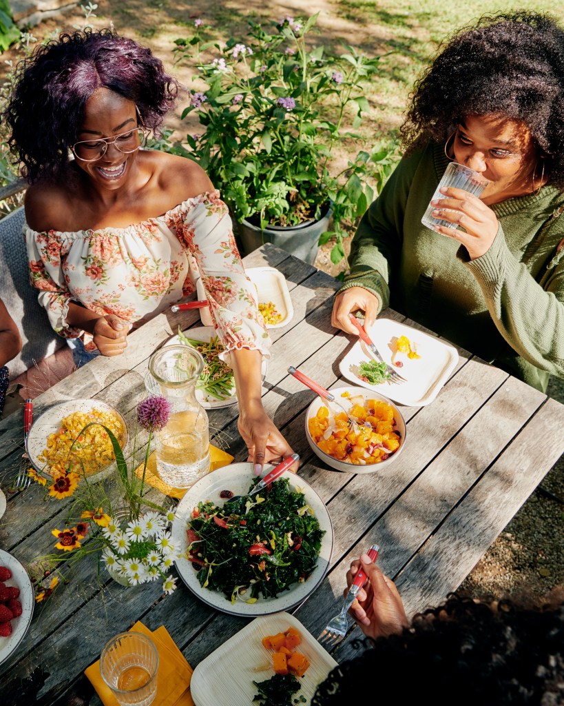 Three Black American women enjoying a meal outside on a warm spring day.