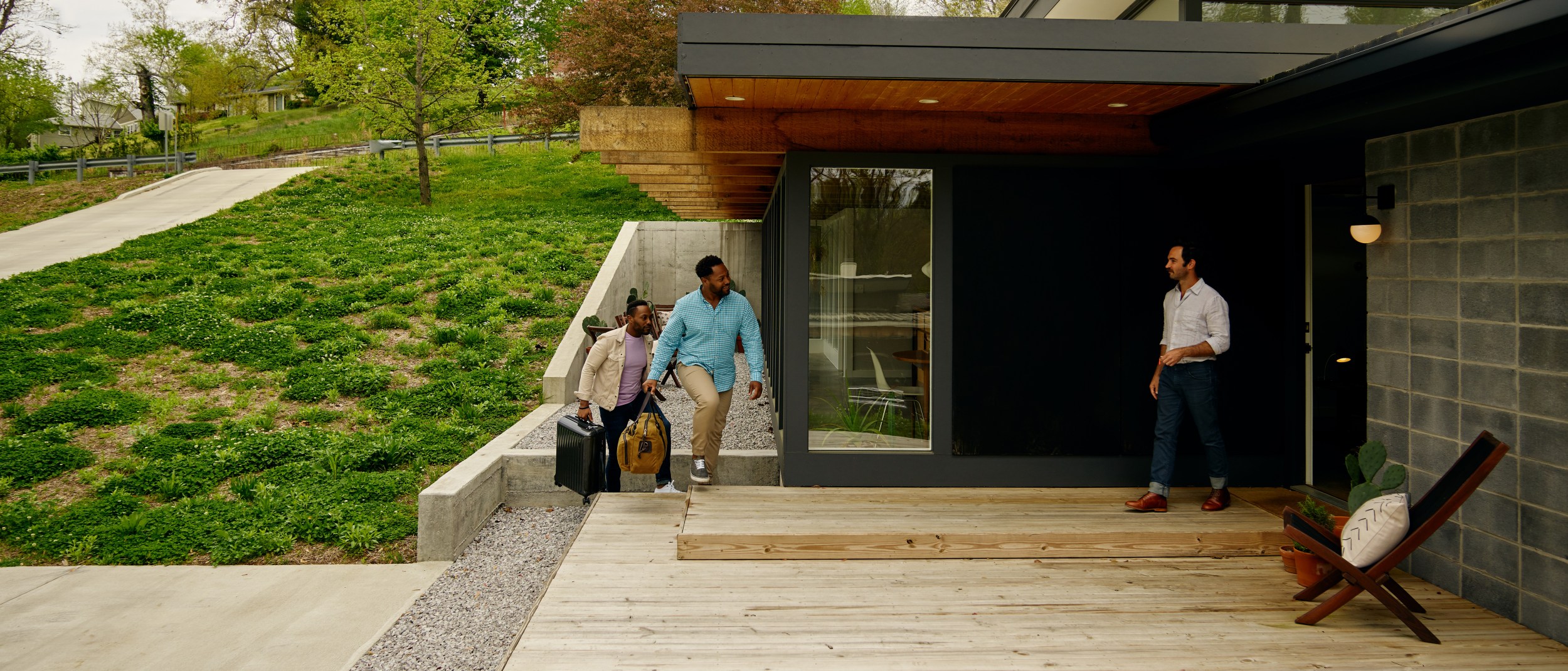 A host welcomes two guests to his modern Airbnb listing.