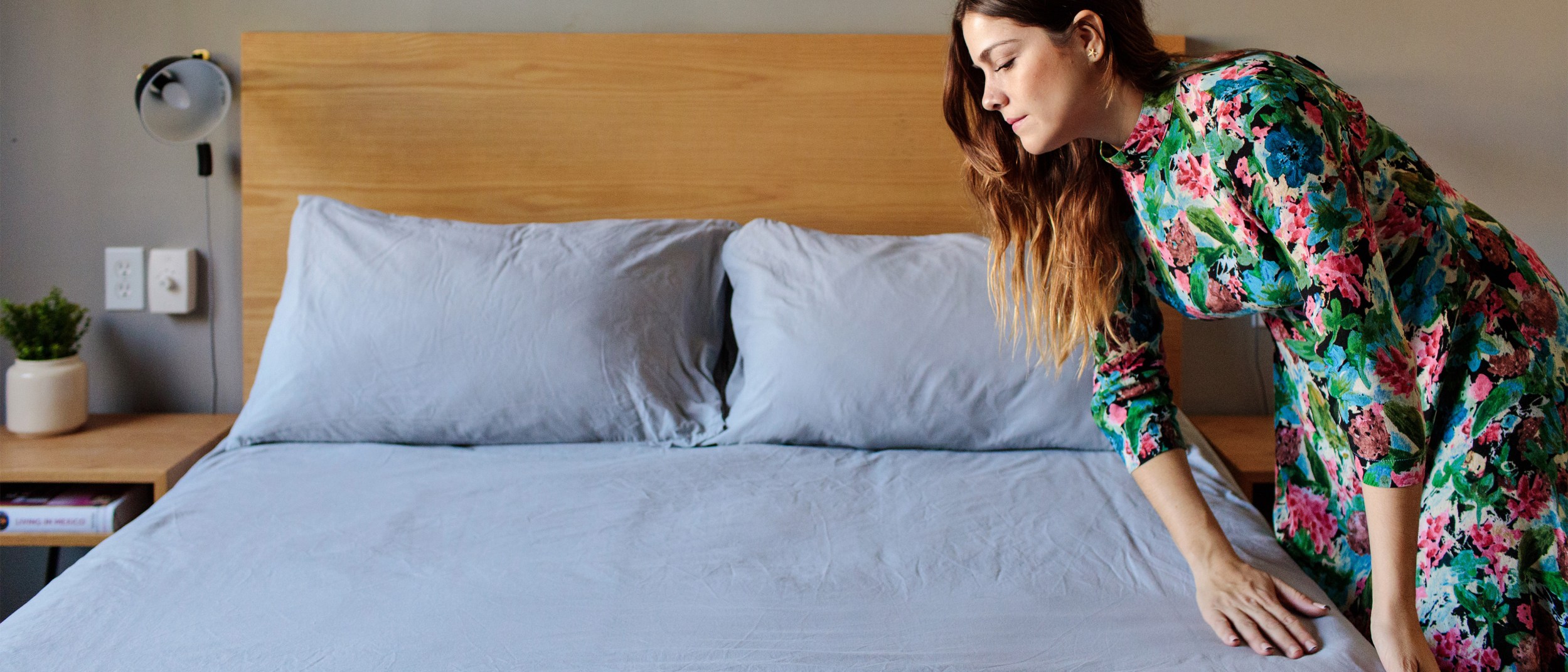 A host smoothes out creases on the sheets of a bed for her upcoming Airbnb guests.