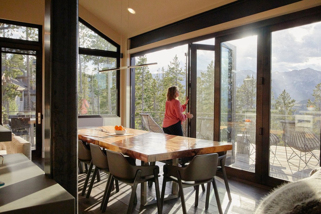 A Airbnb guest opens a door to the deck and admires the view in her listing in Breckenridge, Colorado.