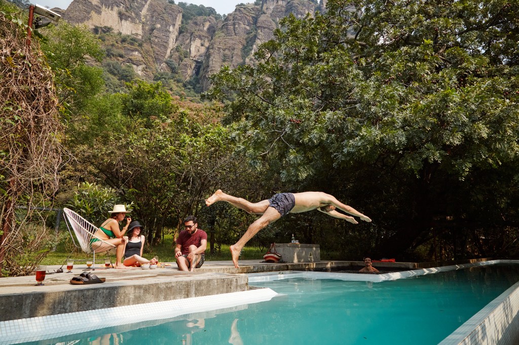 A man dives into a pool while on a summer vacation.