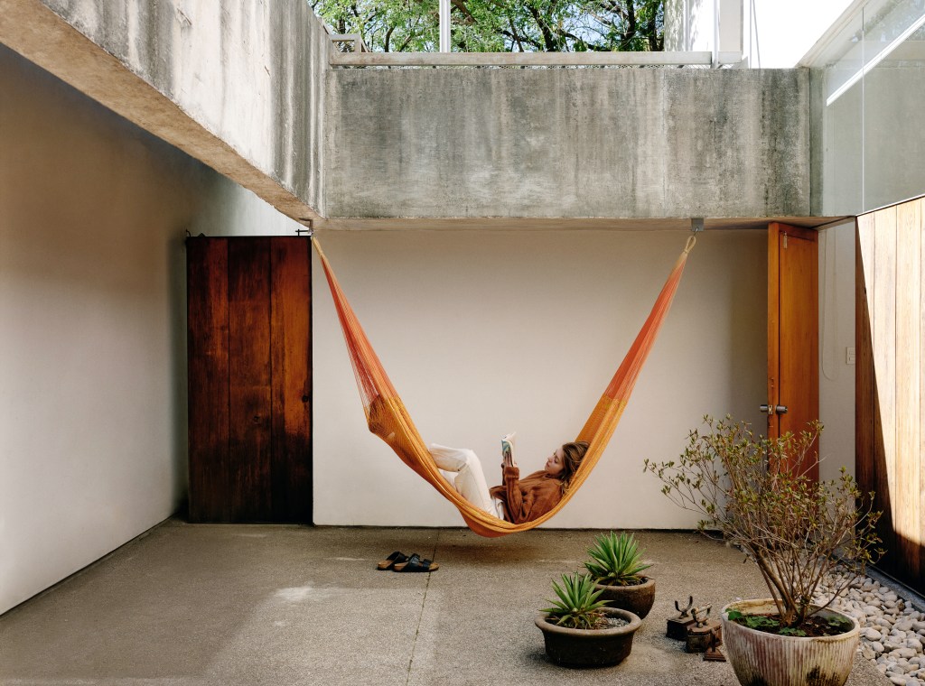 A woman relaxes by reading in a hammock at her Airbnb.