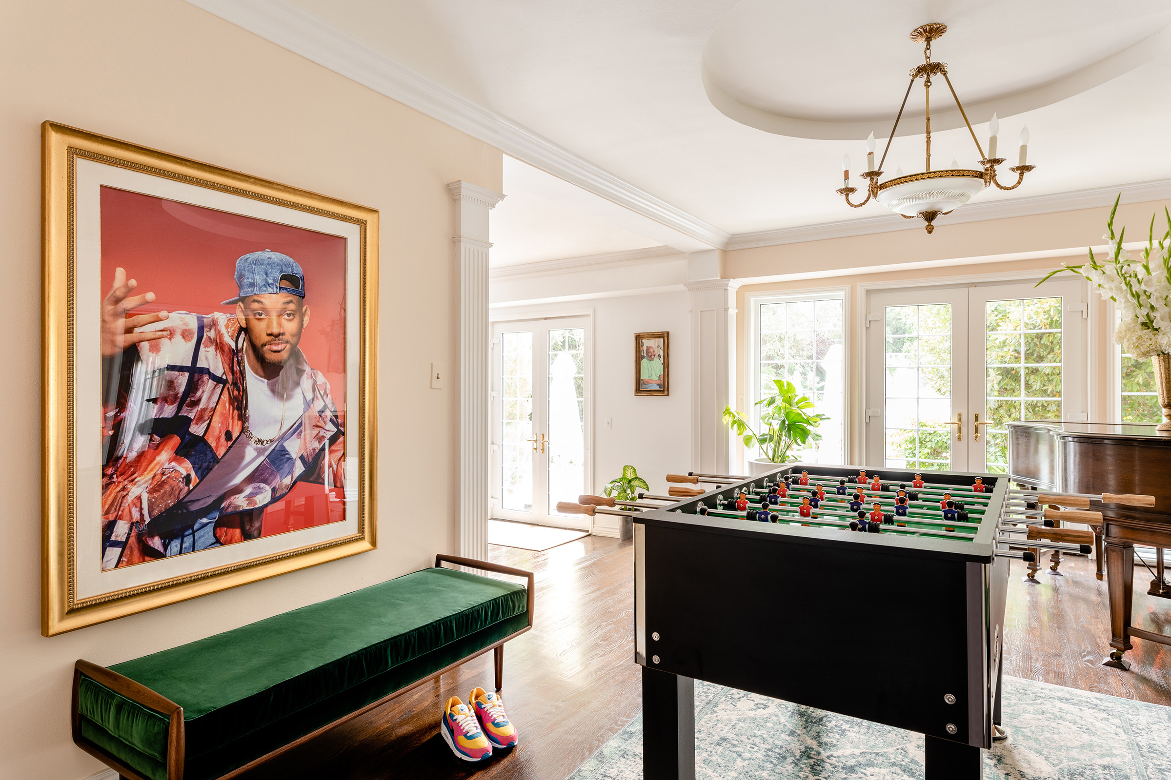 An entryway containing a foosball table and elegantly framed portrait of Will Smith.