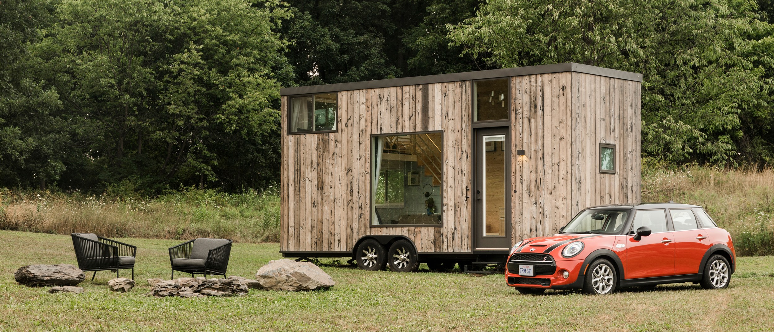 A red MINI Cooper is parked outside of an Airbnb tiny home listing with an outdoor seating area in Marlboro, New York.