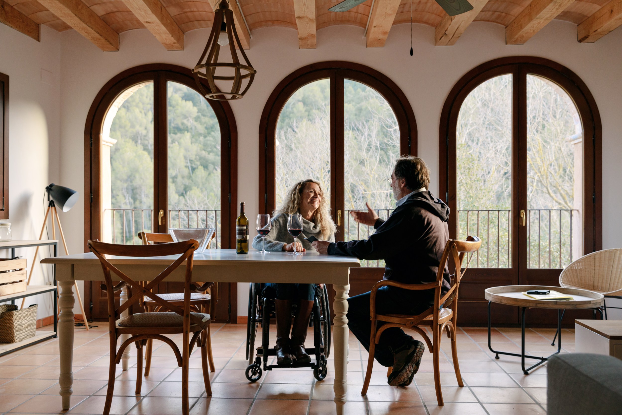 A pair, including a wheelchair user, sat at a kitchen table in Spain