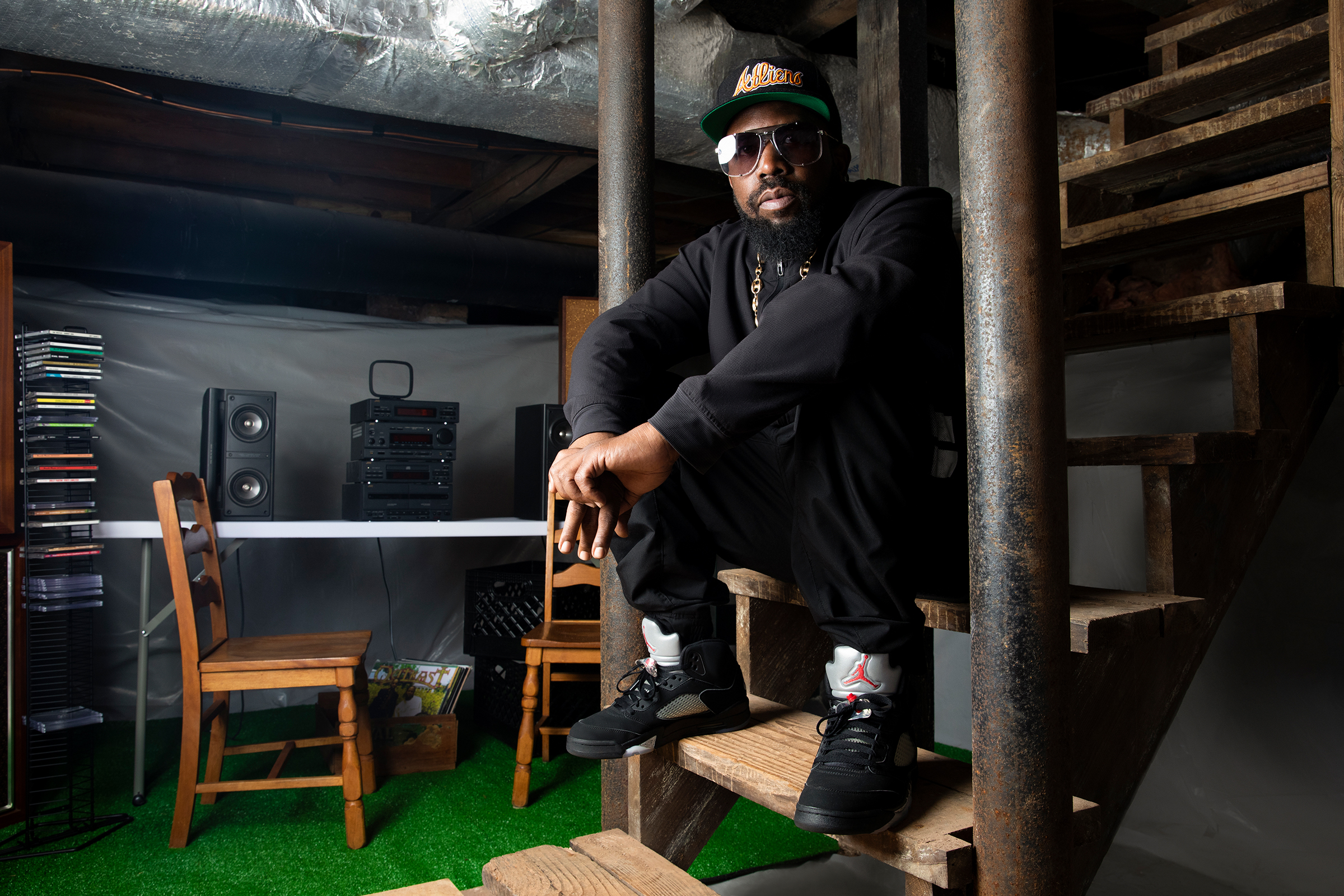 Big Boi sitting on the basement staircase of The Dungeon House with a small mixing table behind him