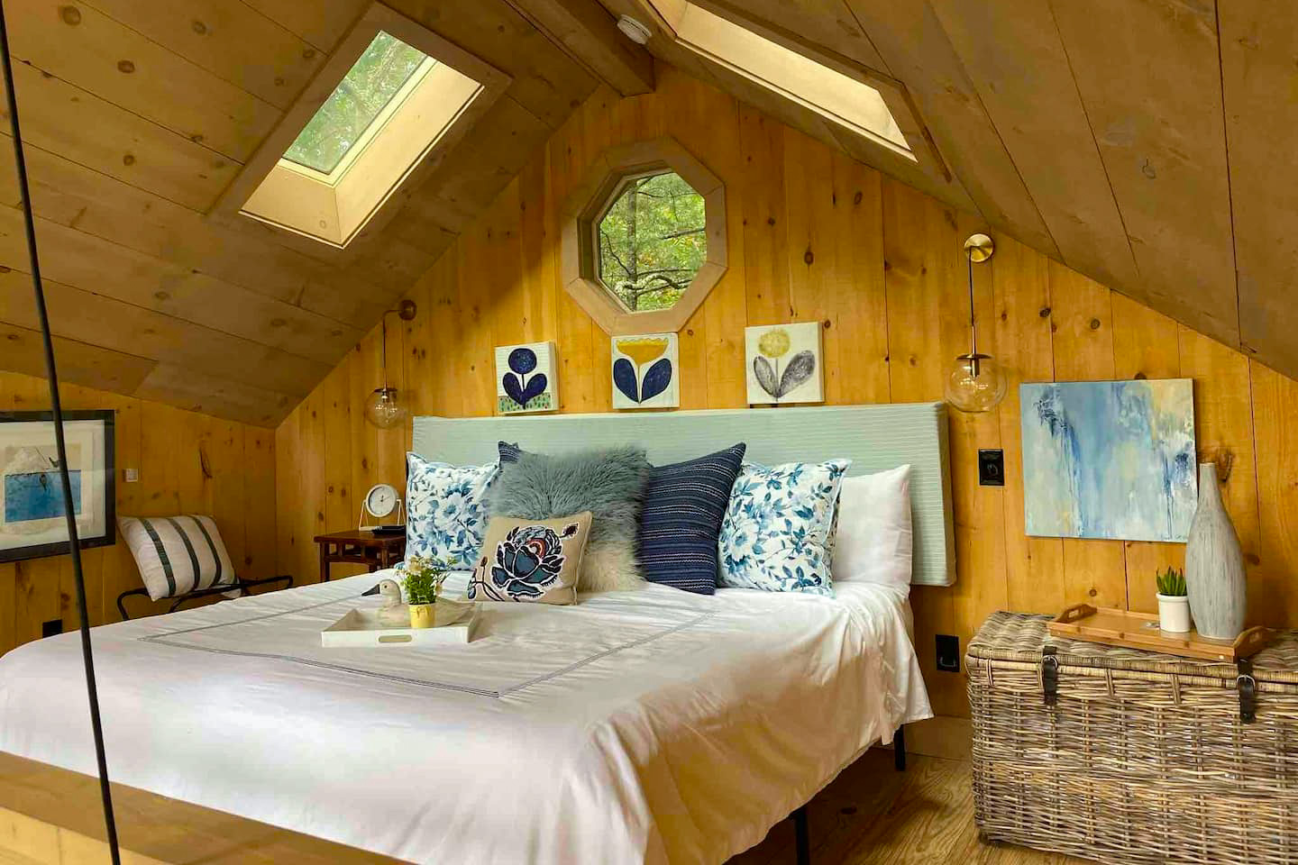 Bed with white sheets and blue pillows situated in a treehouse loft set-up.