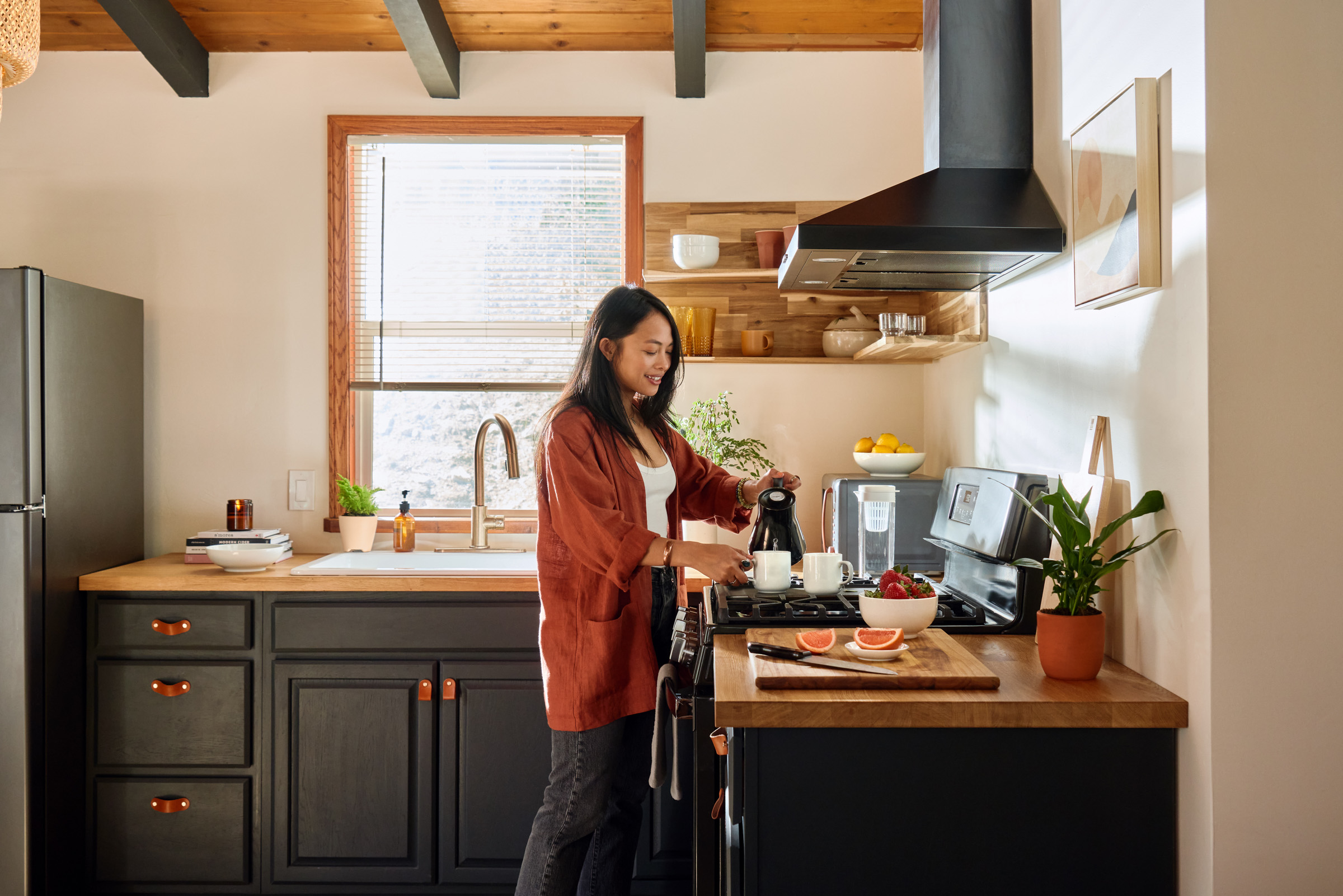 Female guest preparing coffee in the kitchen featuring essential kit mugs and decor. 