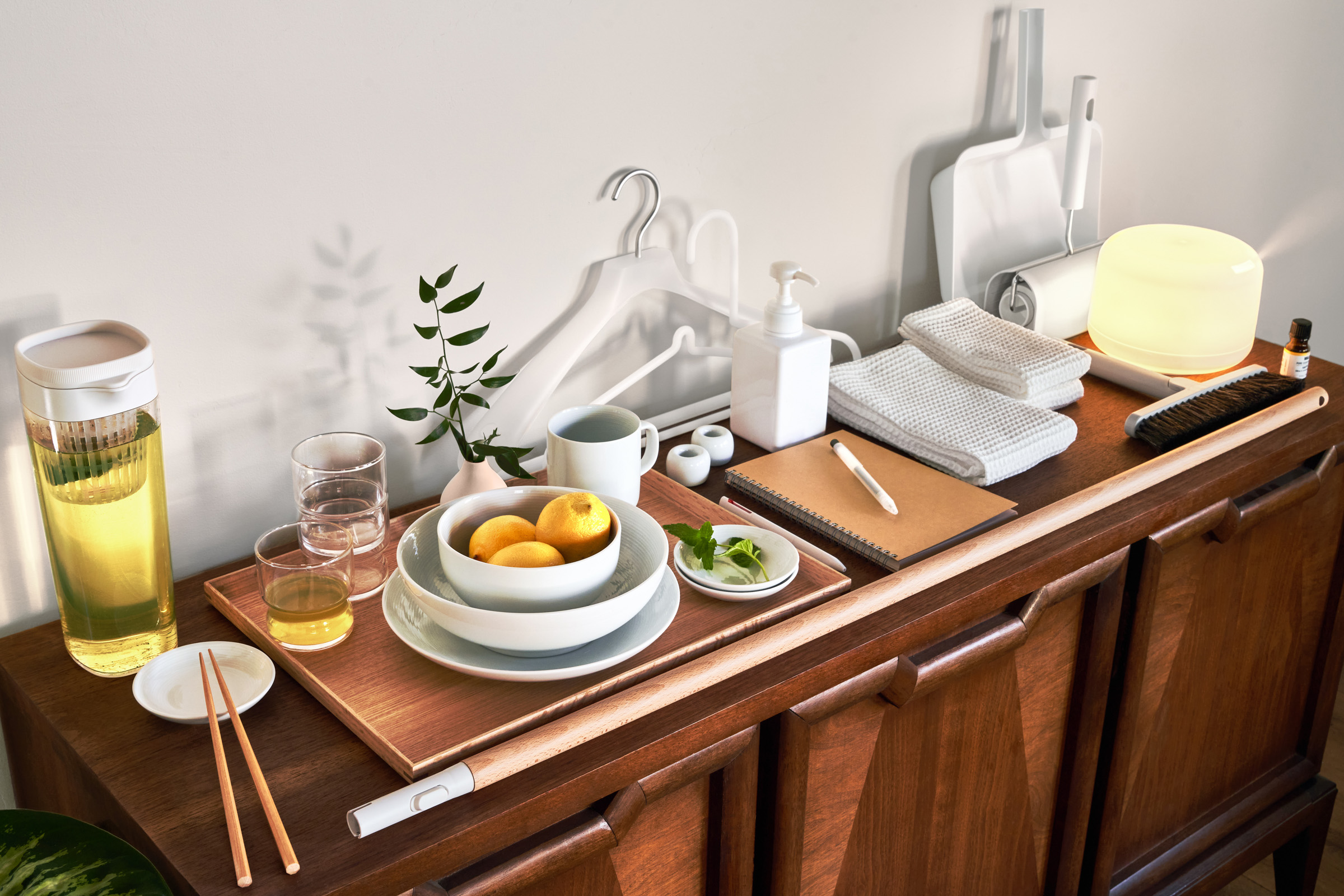 Table with Airbnb and Muji Essential Kit items including bowls, hangers, essential oils and diffuser, and coffee mugs.