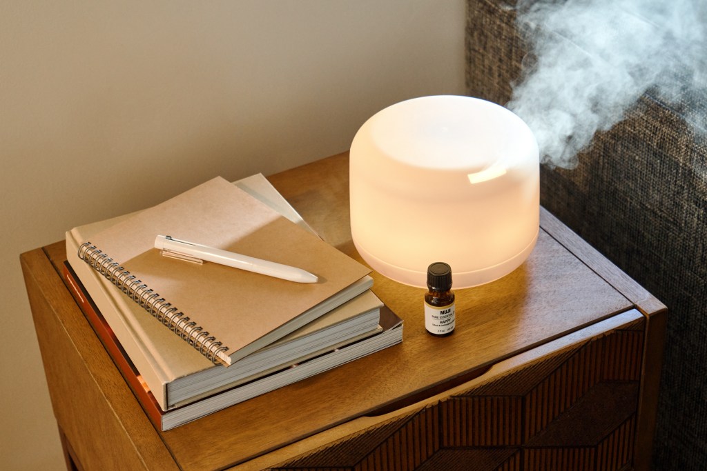 Table with emitting essential oil diffuser and notebooks and a pen, which are part of the kit.