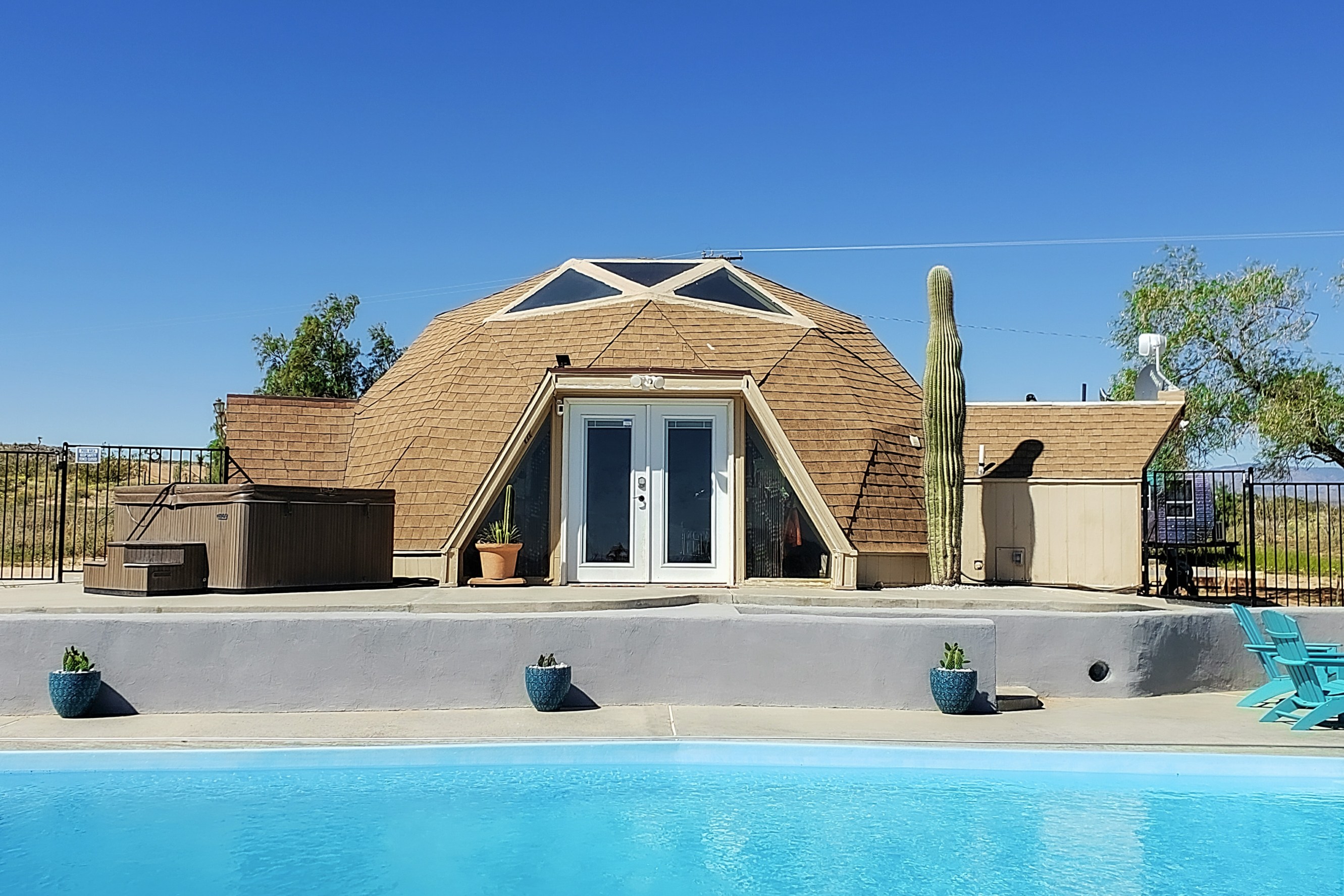 Dome house with swimming pool in the foreground and desert landscape in the background.