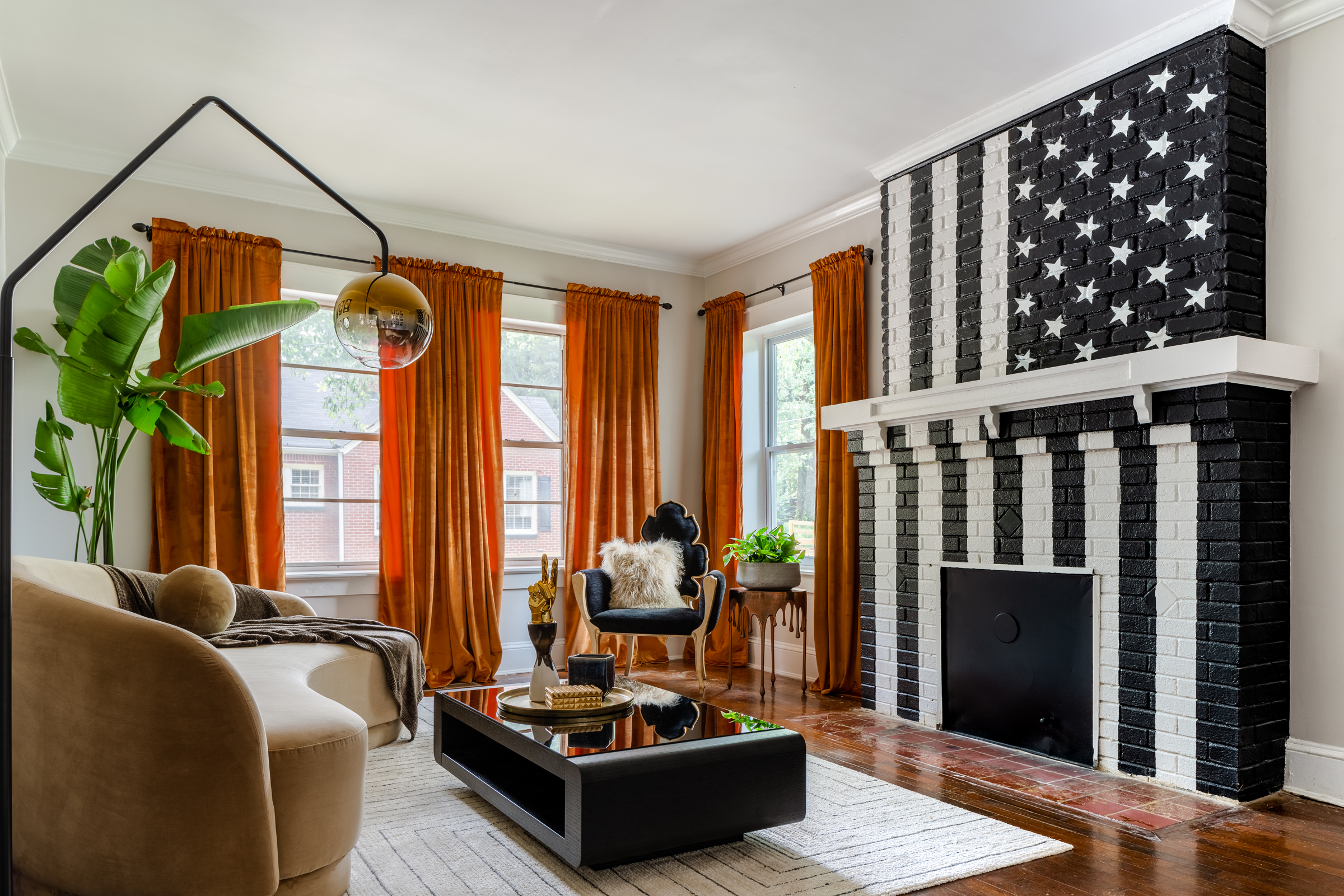 Living room with black and white flag fireplace design, brown chairs in foreground and orange drapes