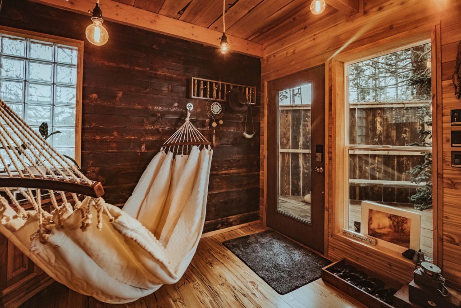 Wood cabin entryway with a hammock hanging from the walls.