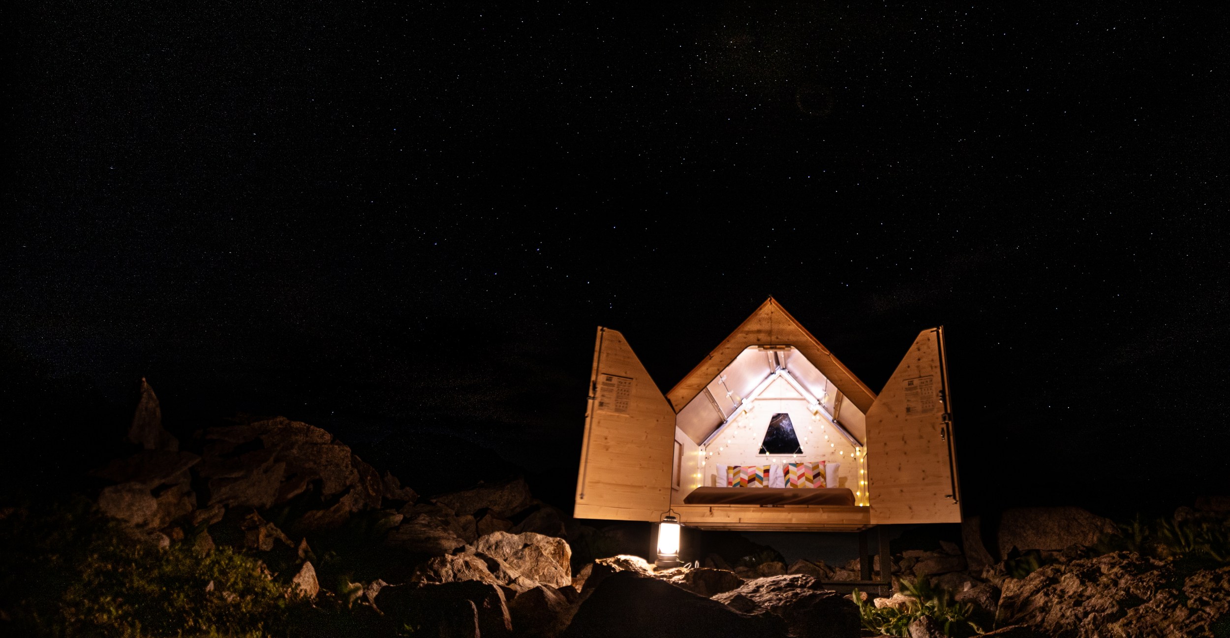 Wooden tiny house at night in situ at its location in the Italian Alps.