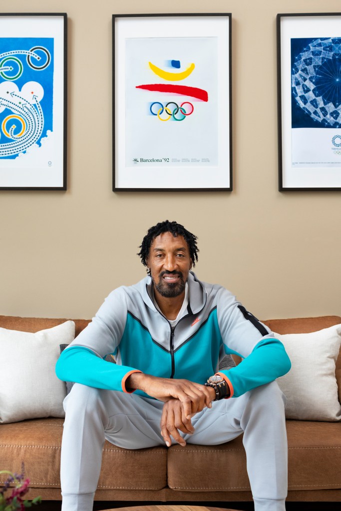 Scottie Pippen sits on a couch with a poster from the 1992 Olympic games hung on the wall behind him.