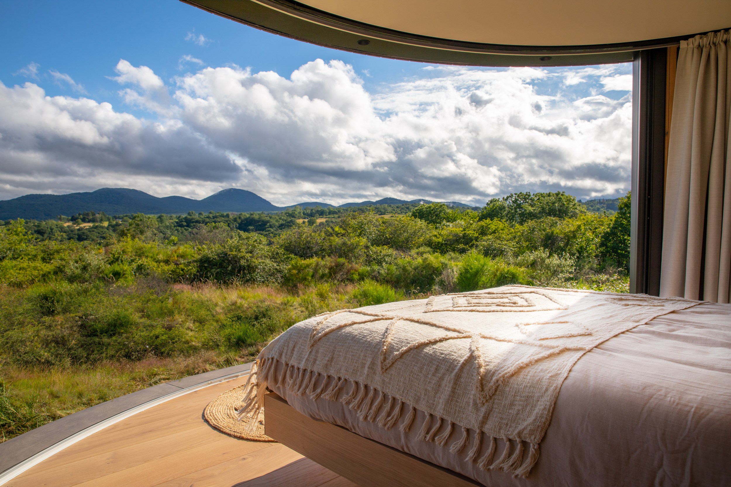 Interior of mini home showing panoramic bedside view of the Chaîne des Puys Volcanoes.