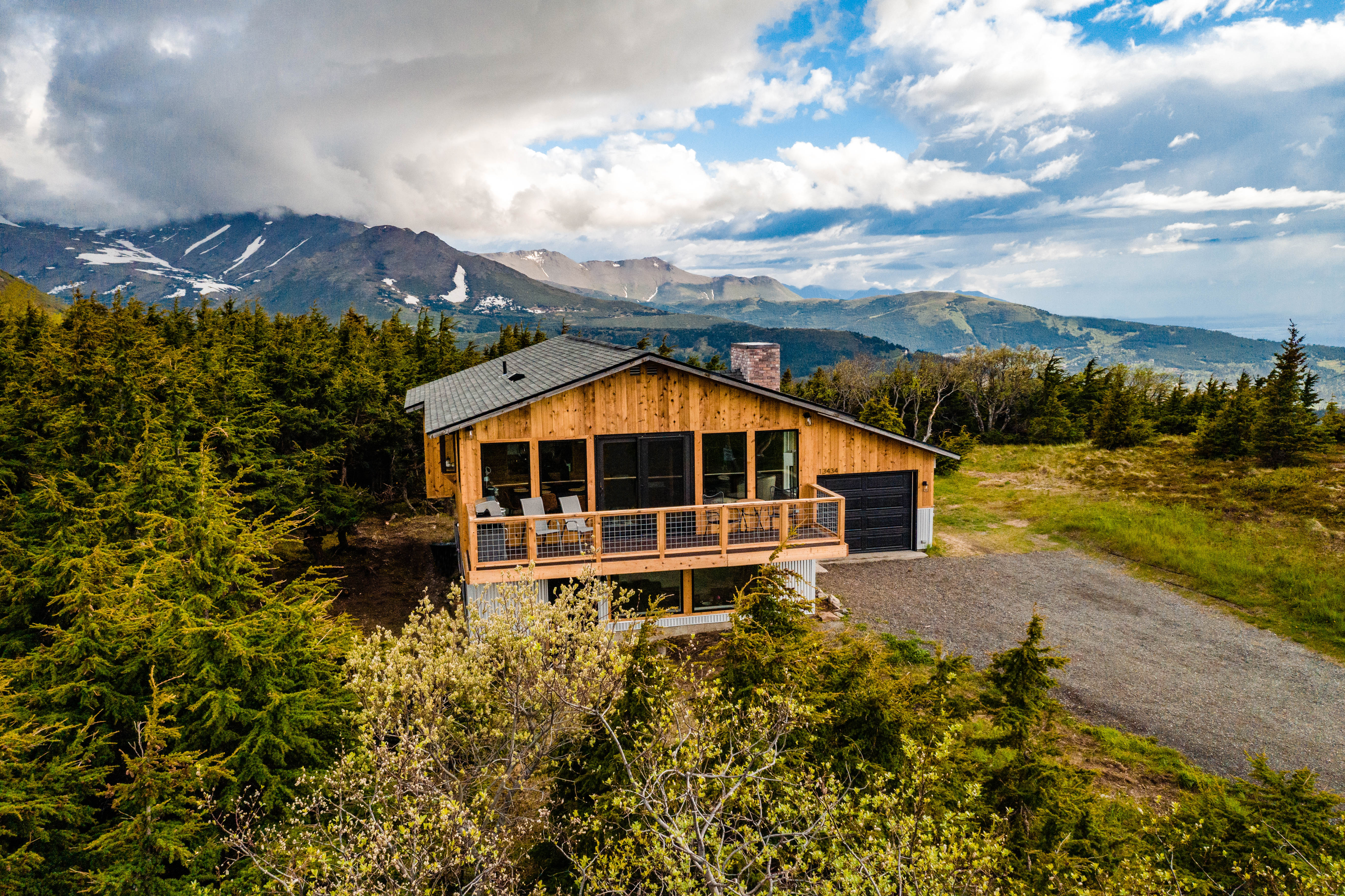White pine lodge nestled amongst green alpine forests and mountains in the background.