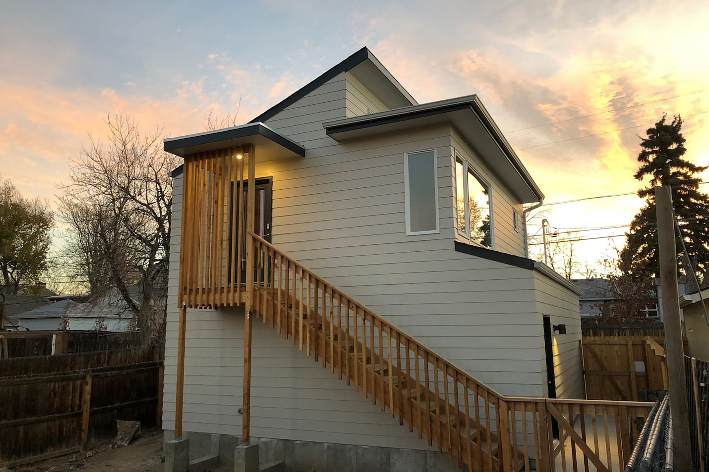 A white, two story home set in front a setting sun.
