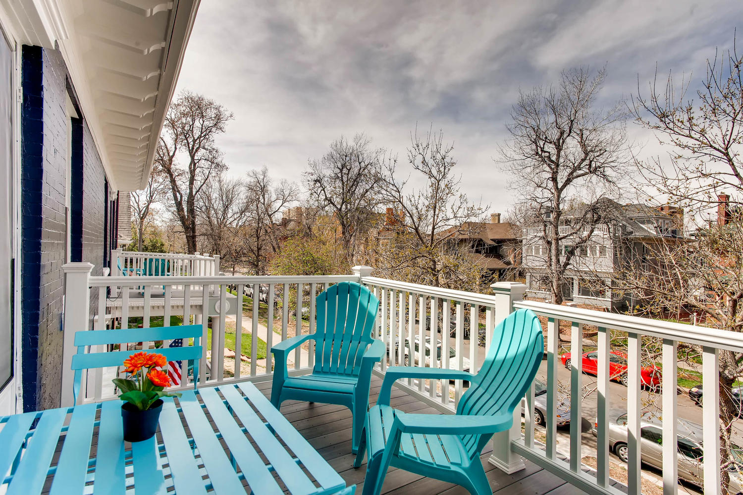 Balcony featuring teal blue outdoor furniture include two chaise lounge chairs with a neighborhood scene in the back.