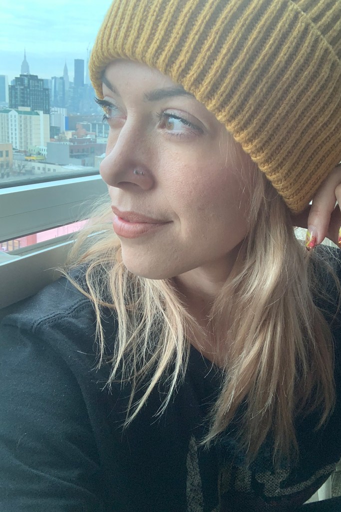 Host Jennifer wearing a yellow beanie looking outside what appears to be a train car window.