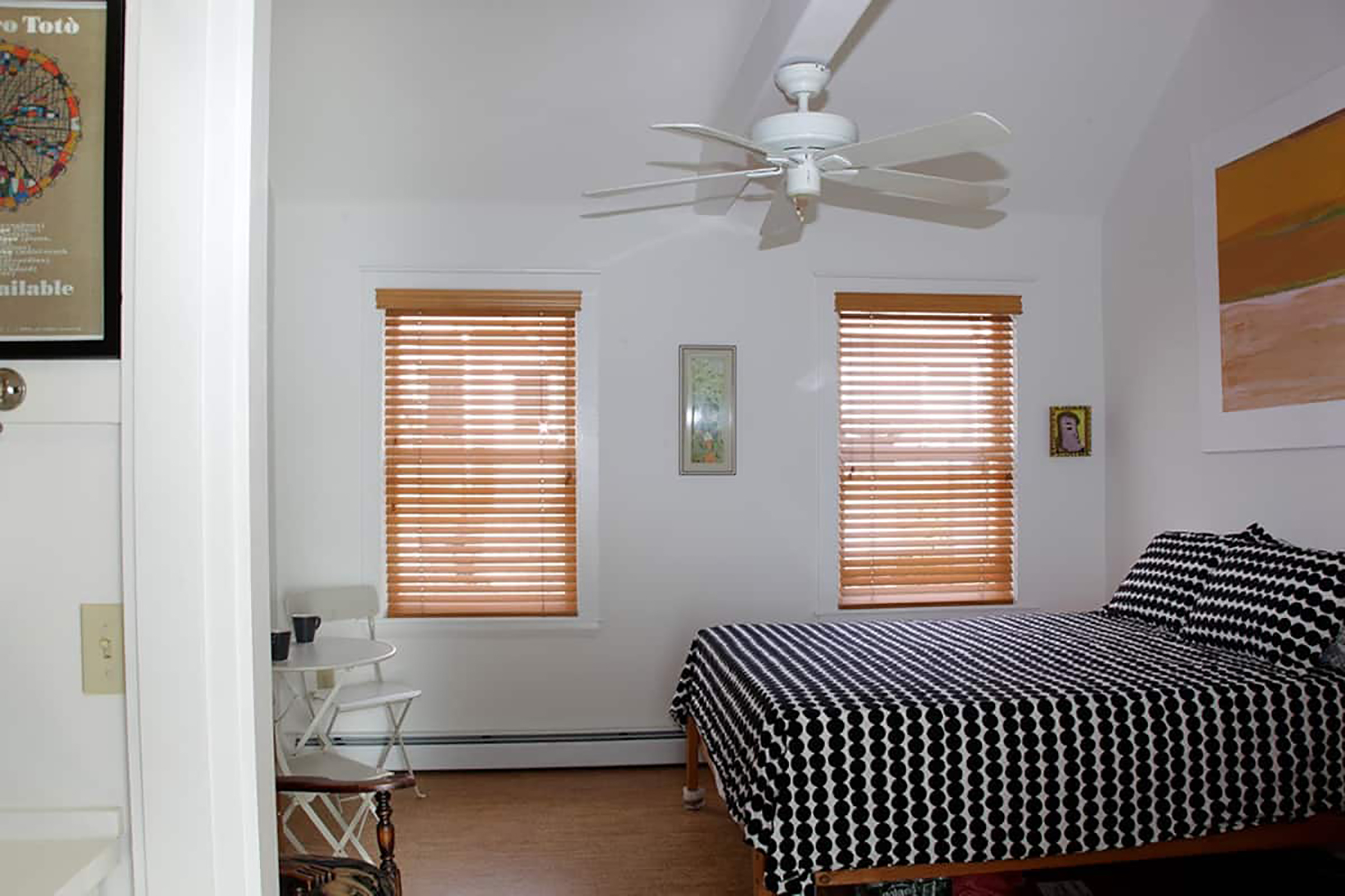 A bed with black and white polka dot sheets in a room with white walls.