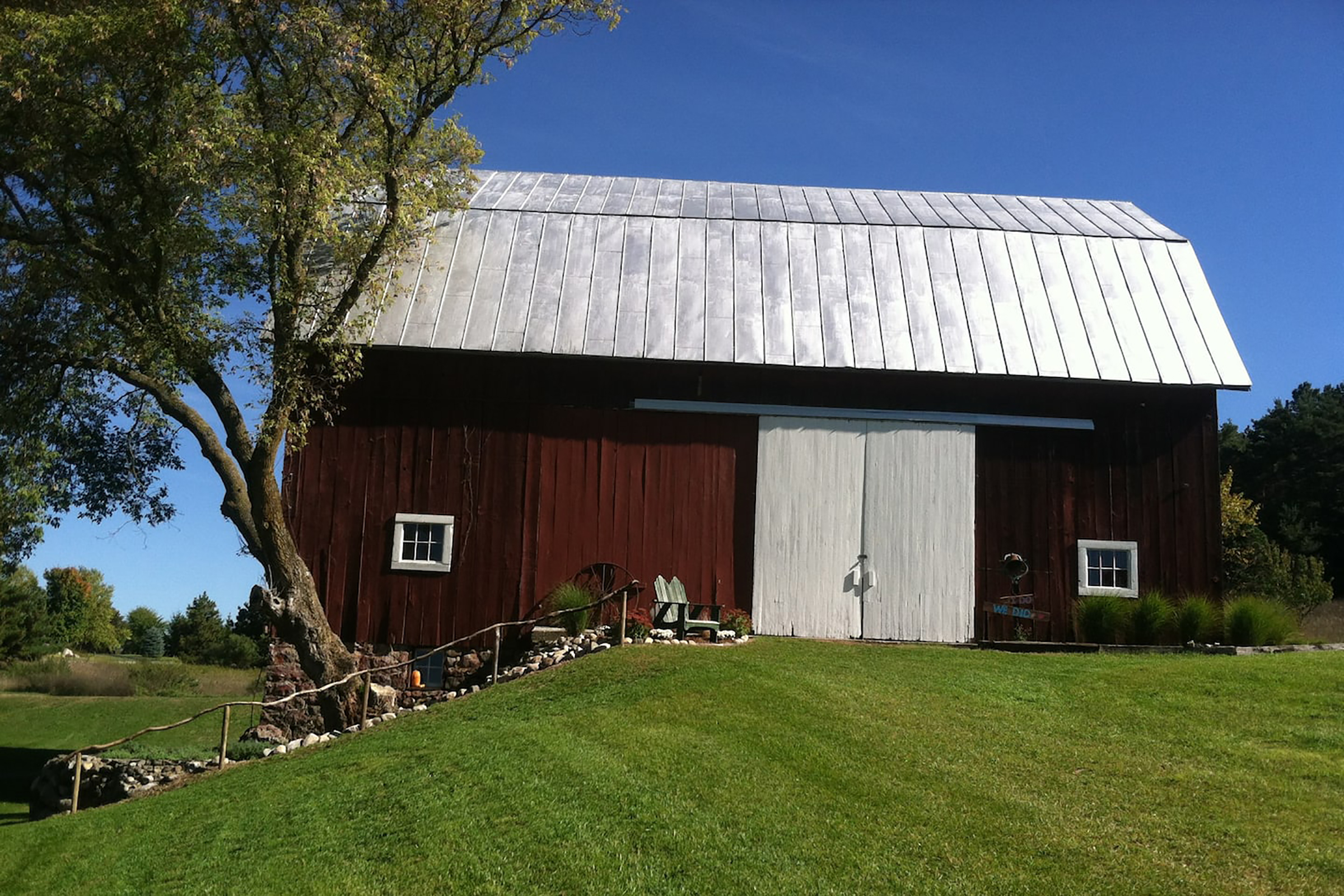 A large barn with tall white doors and an expansive green grass yard.