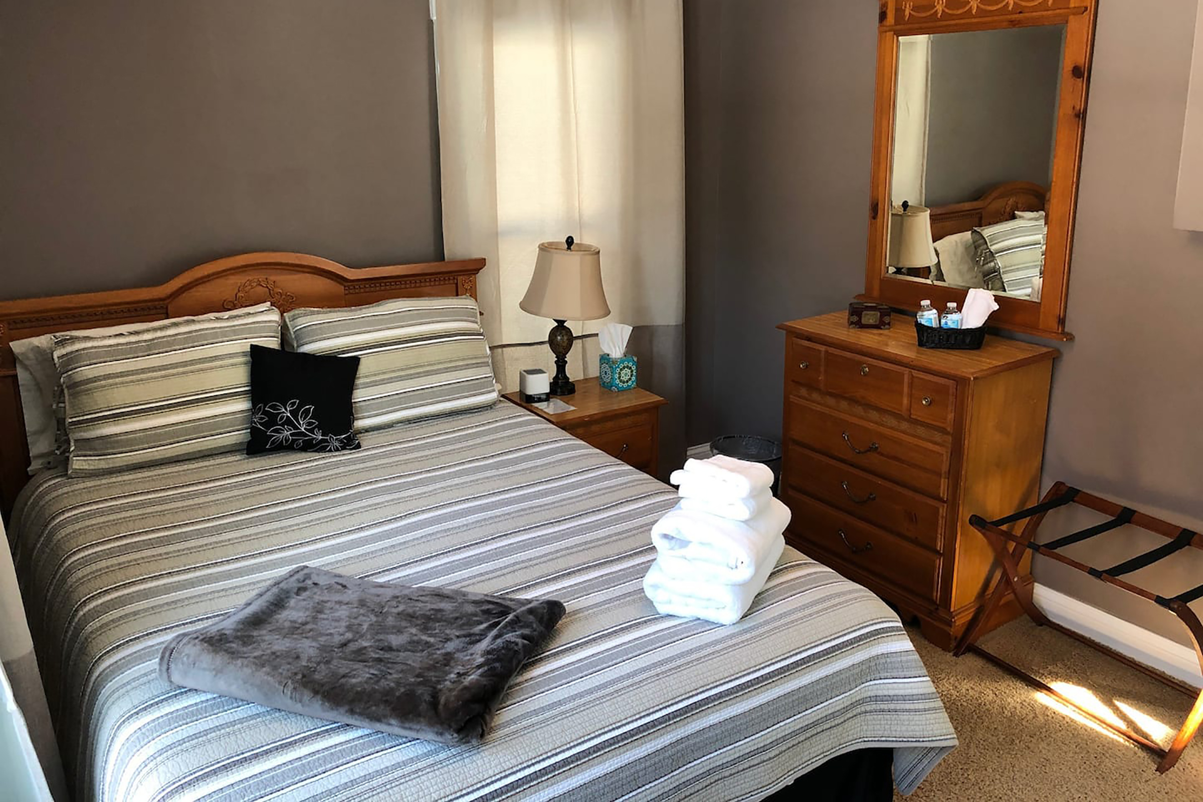 A bed with gray striped sheets with folded white towels on top