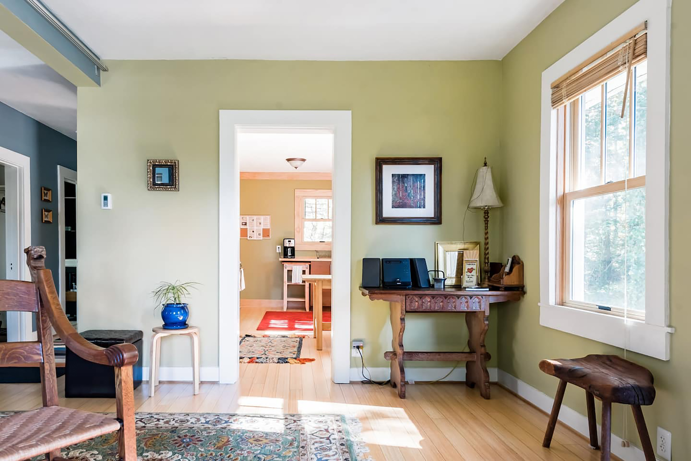 A living room with soft green colored walls and dark, wooden furniture