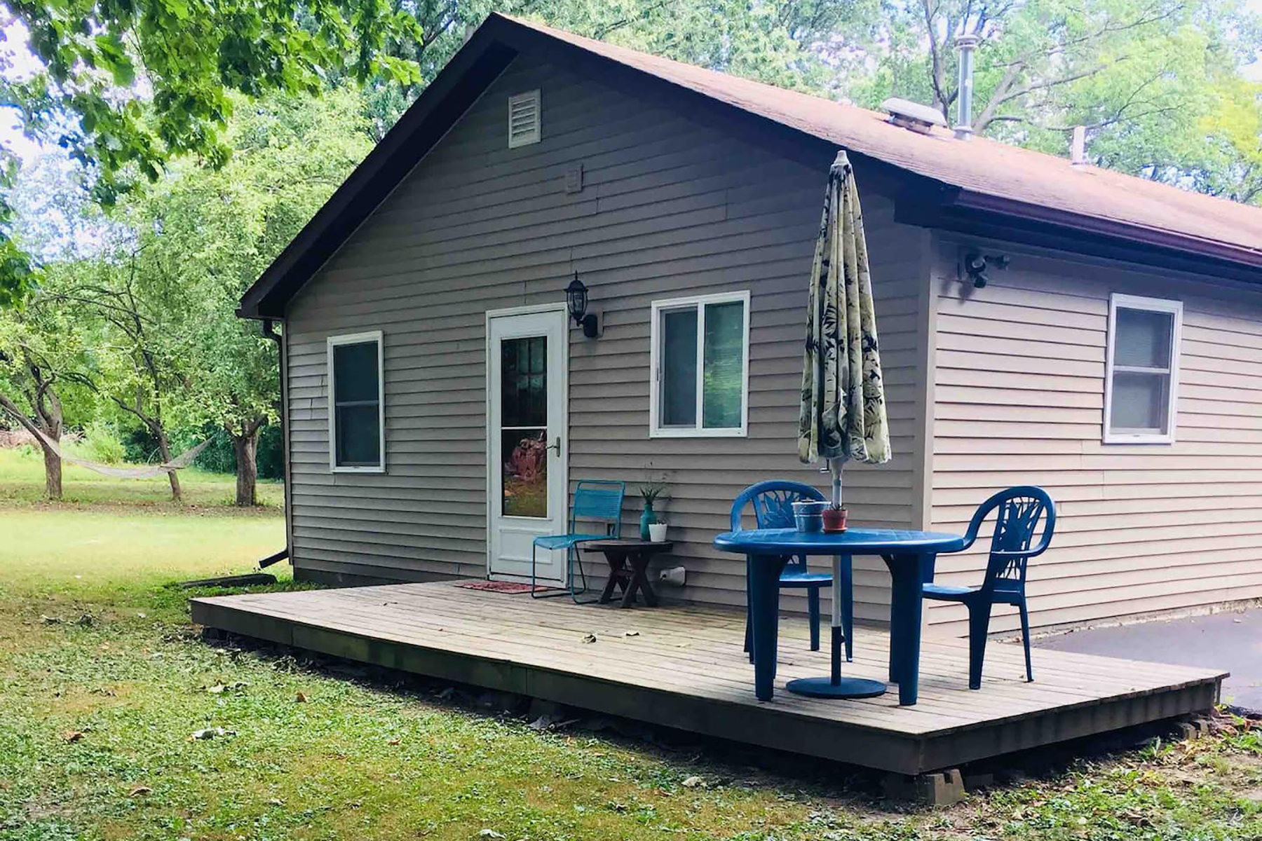 A tan colored home with a back porch and blue patio furniture.