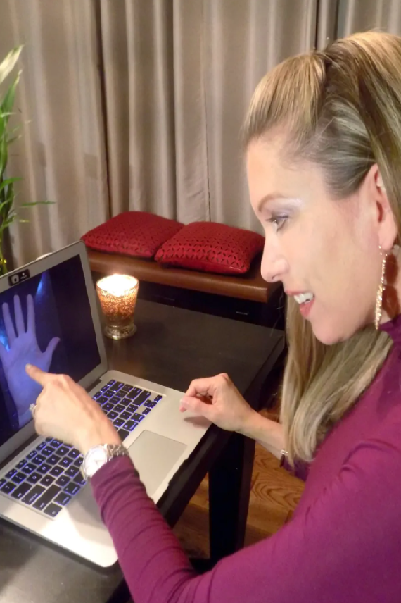 Woman pointing at a palm through a laptop screen