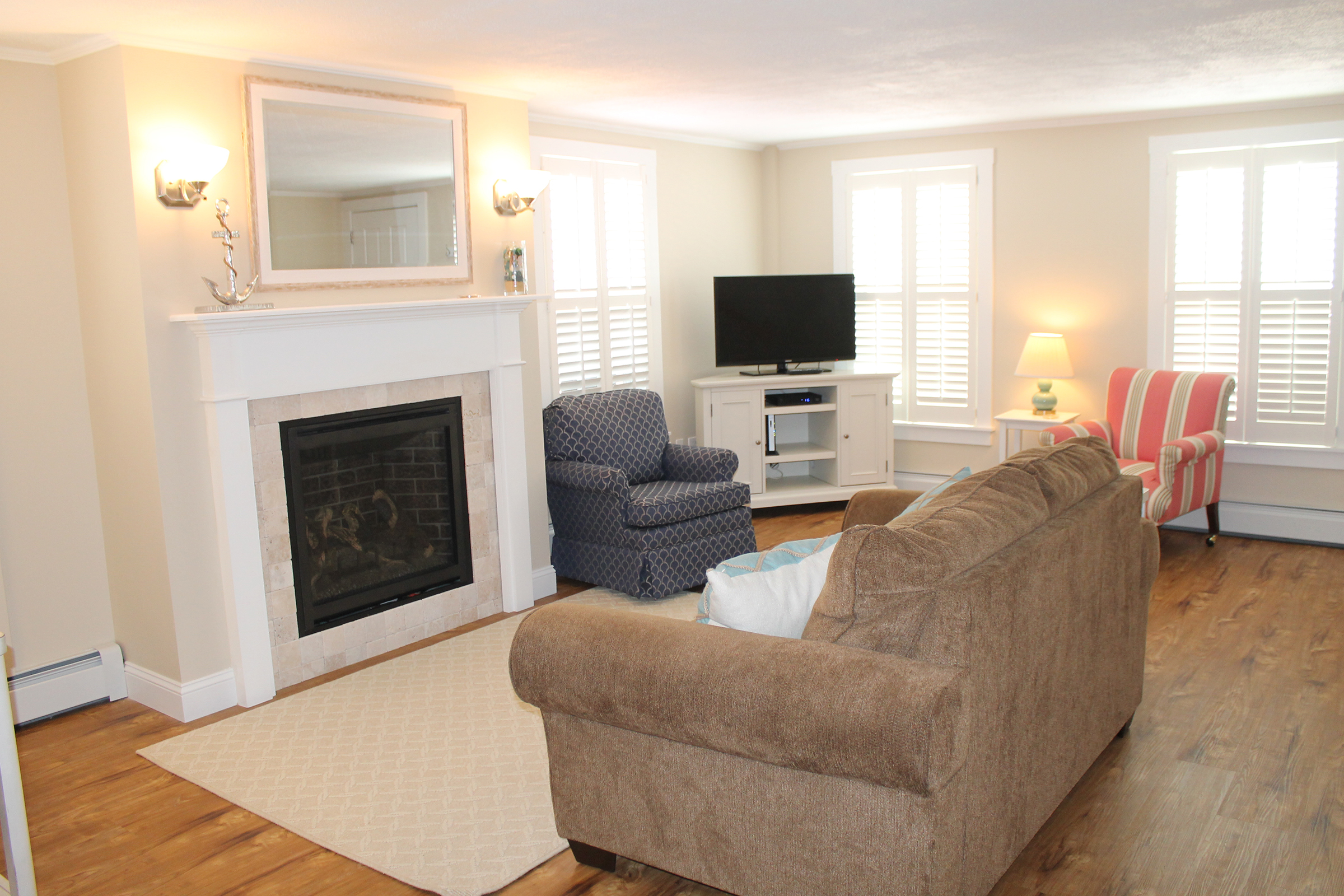 A tan sofa in a living room with a fireplace and television.