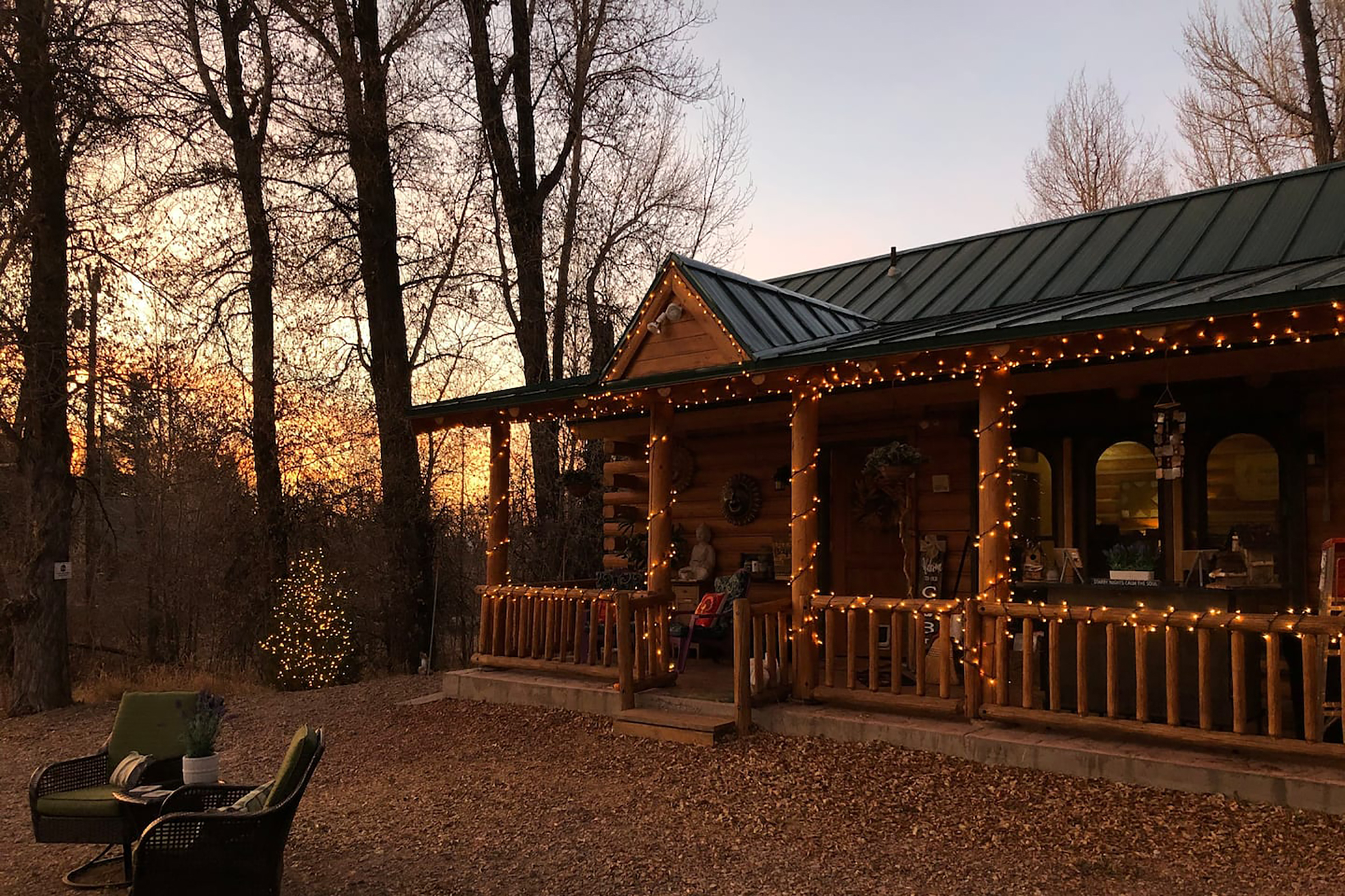 The sun setting over a cabin with string lights hanging across the front of the house.