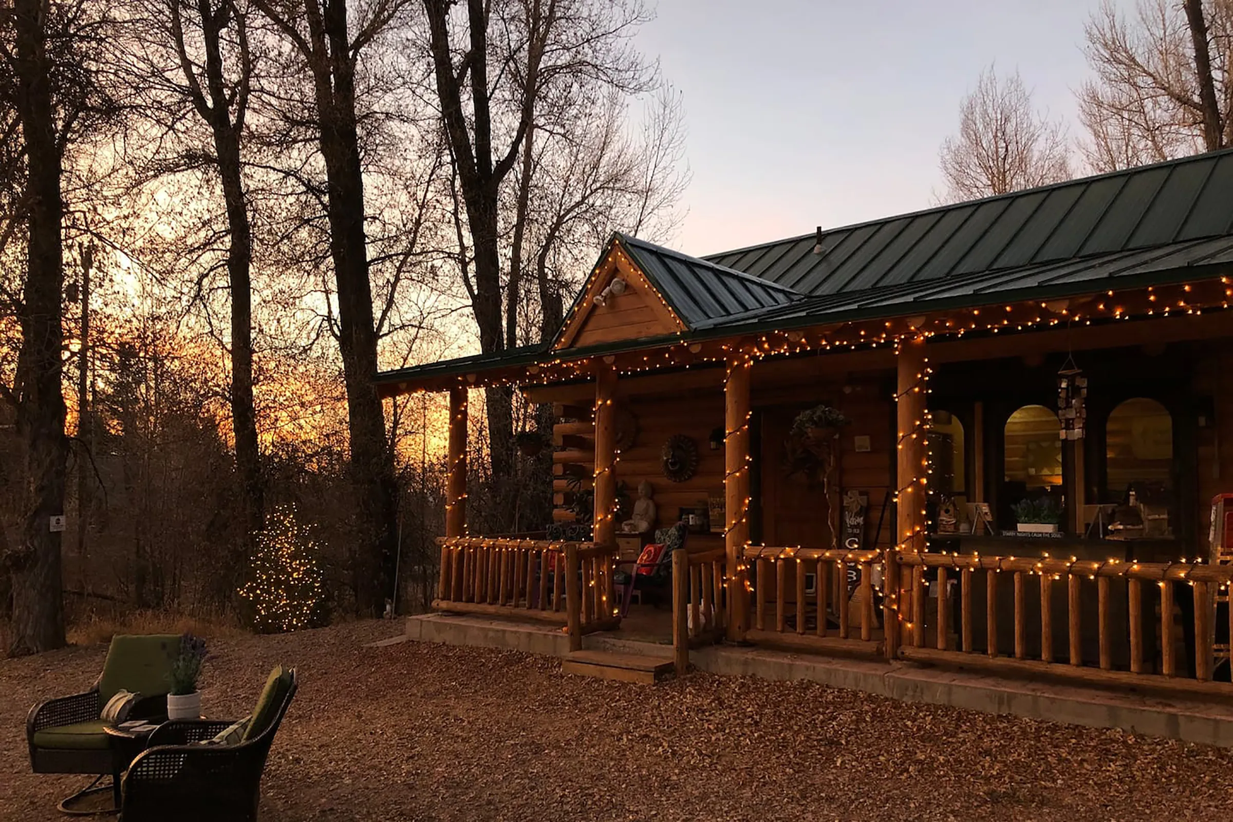 The sun setting over a cabin with string lights hanging across the front of the house. 