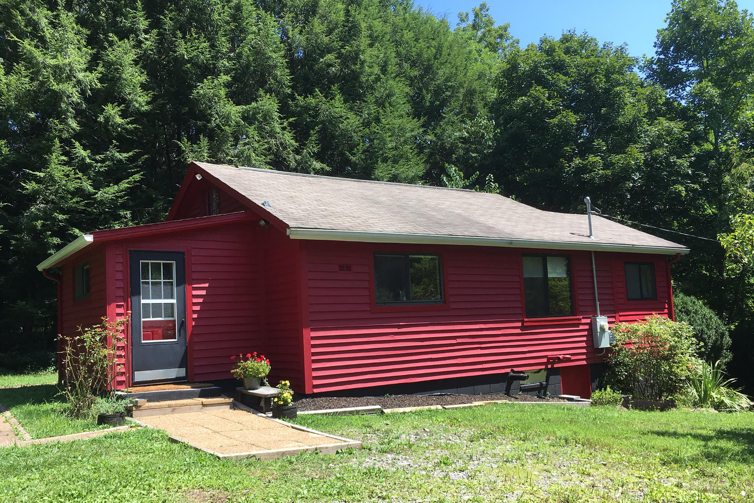 A red colored ranch home with a black door.