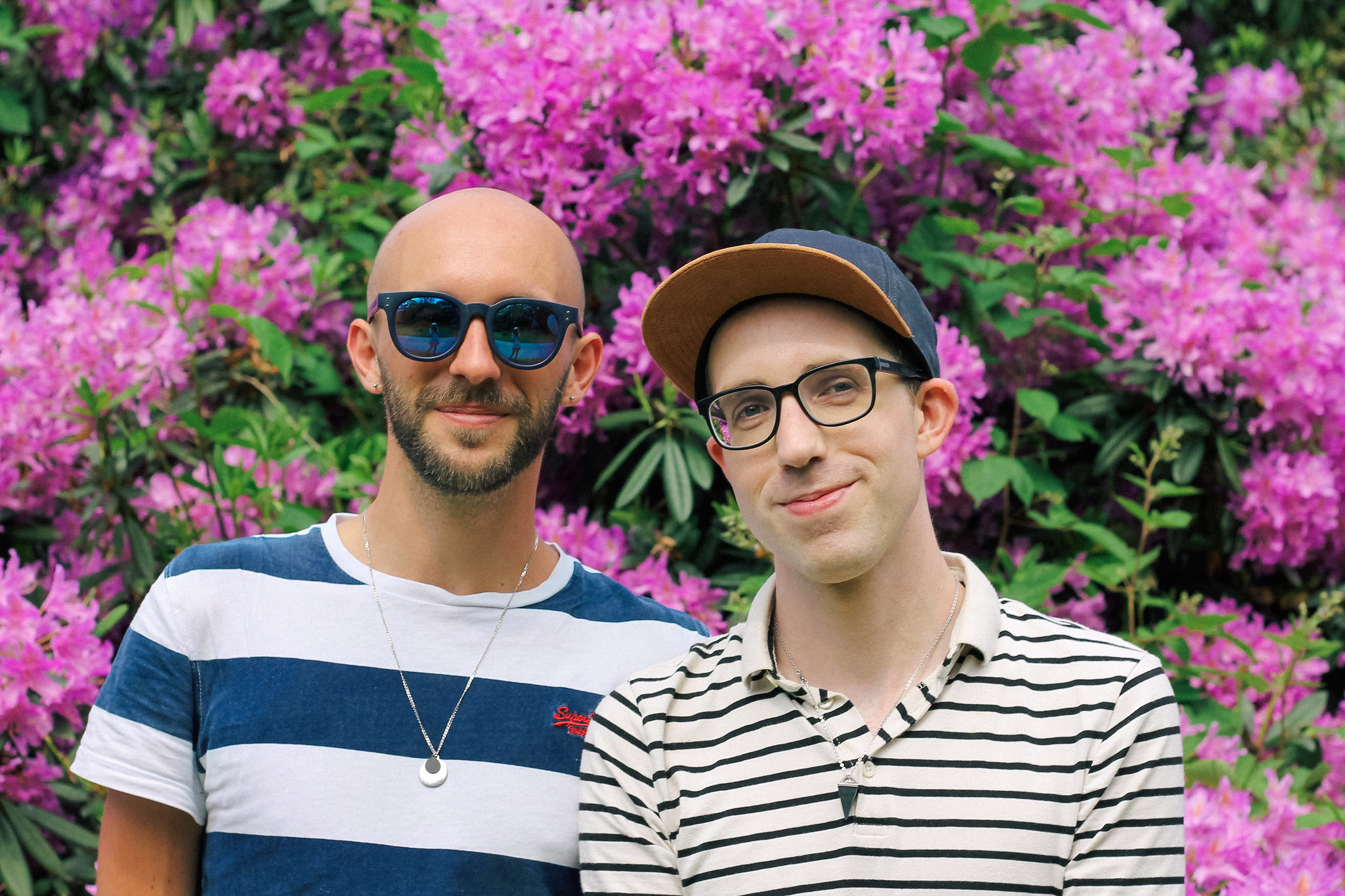 Will and Steven standing in front of a wall of purple flowers.