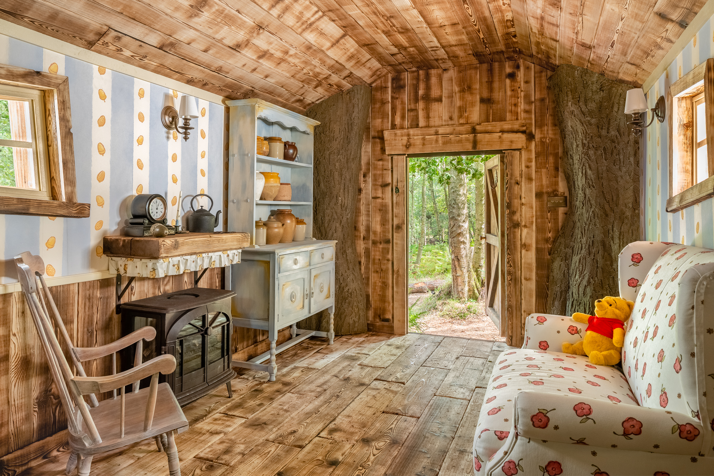 Interior shot of Winnie the Pooh's house, showing specially designed sofa with flower-patterned upholstery, a stove and a kitchen dresser laden with honey pots.