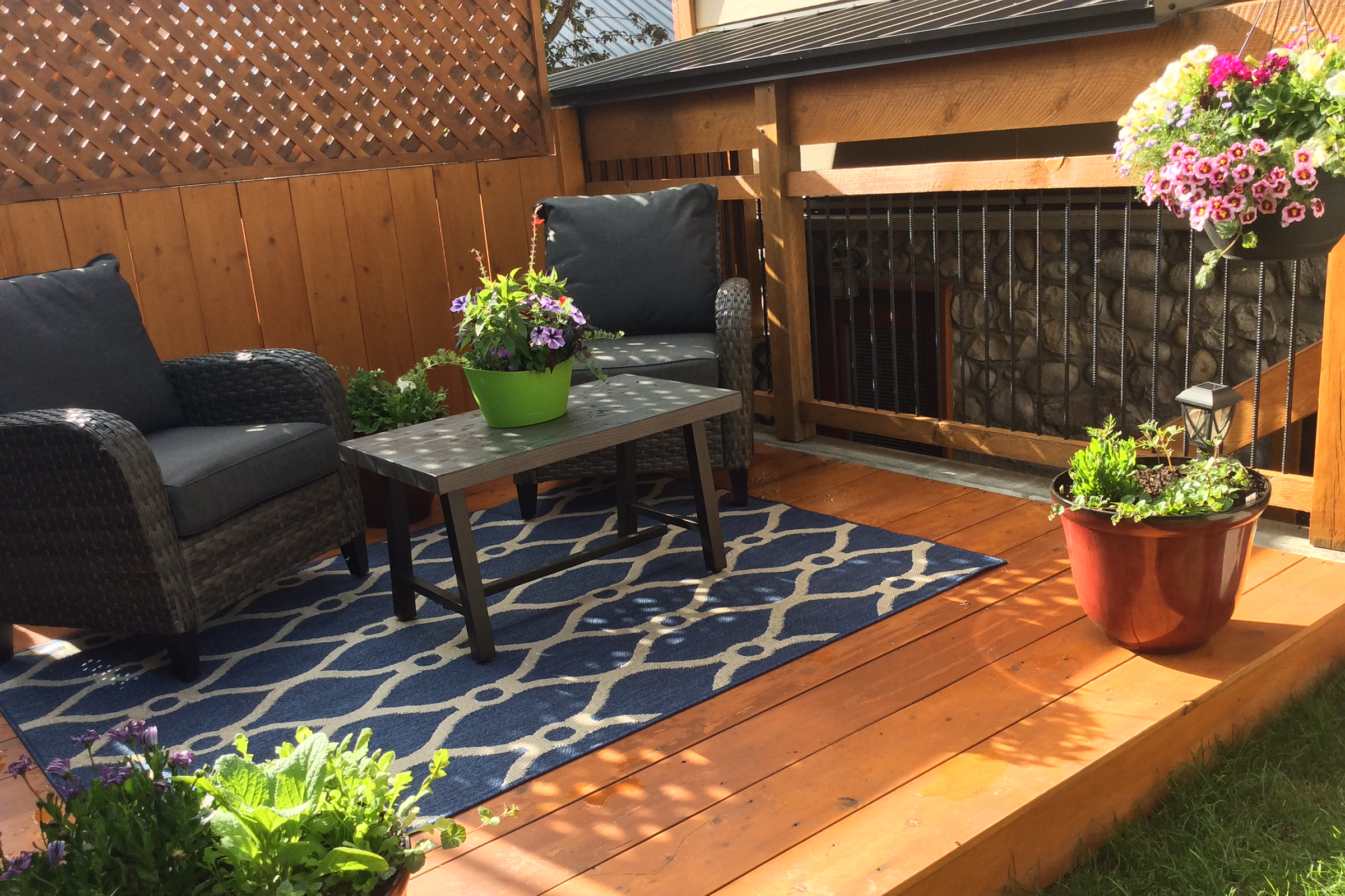 Backyard porch with navy lawn furniture and potted plants.