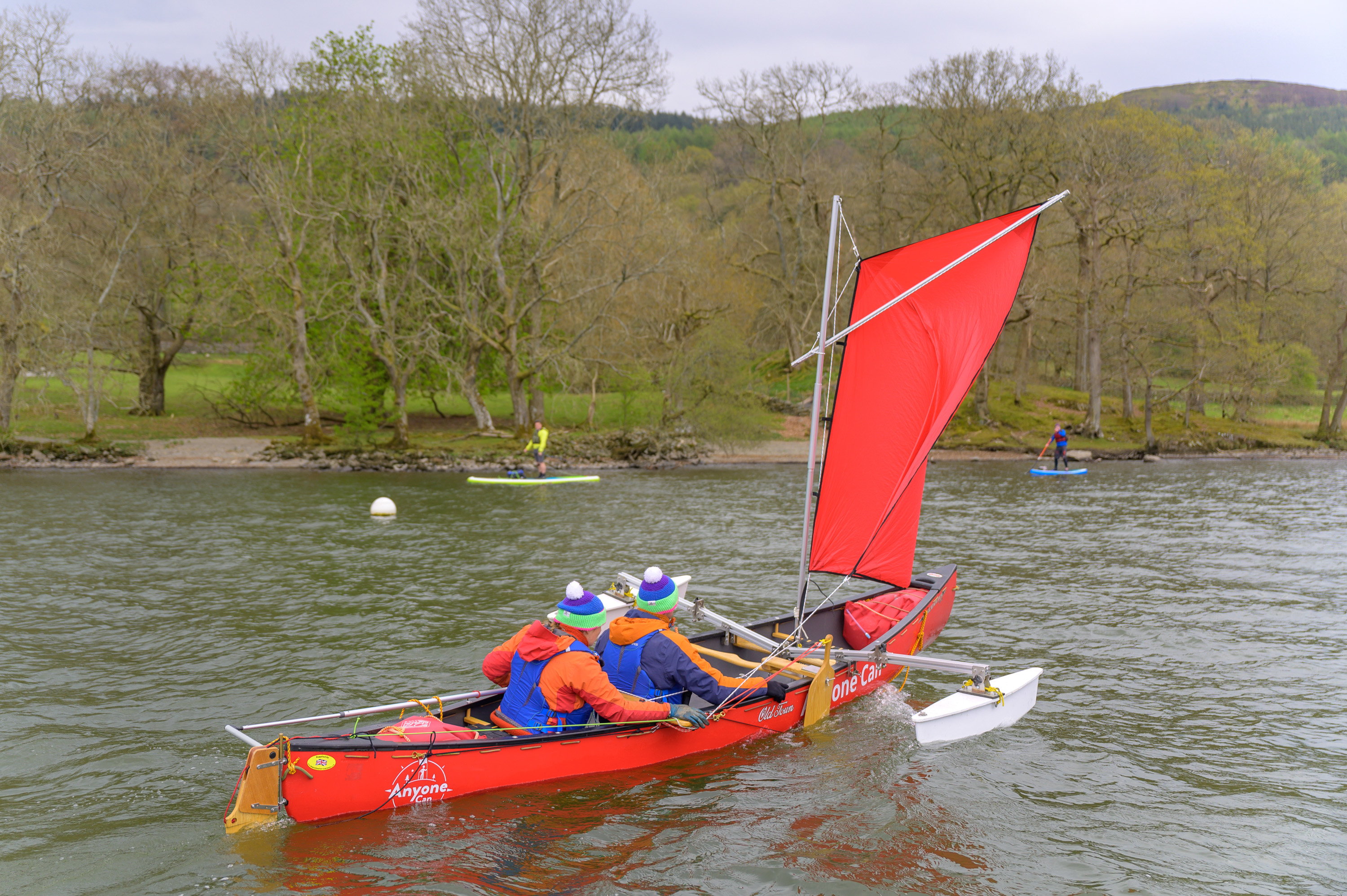 A group of people in a red canoe sailboat as part of an Airbnb Experience that accommodates accessibility needs.