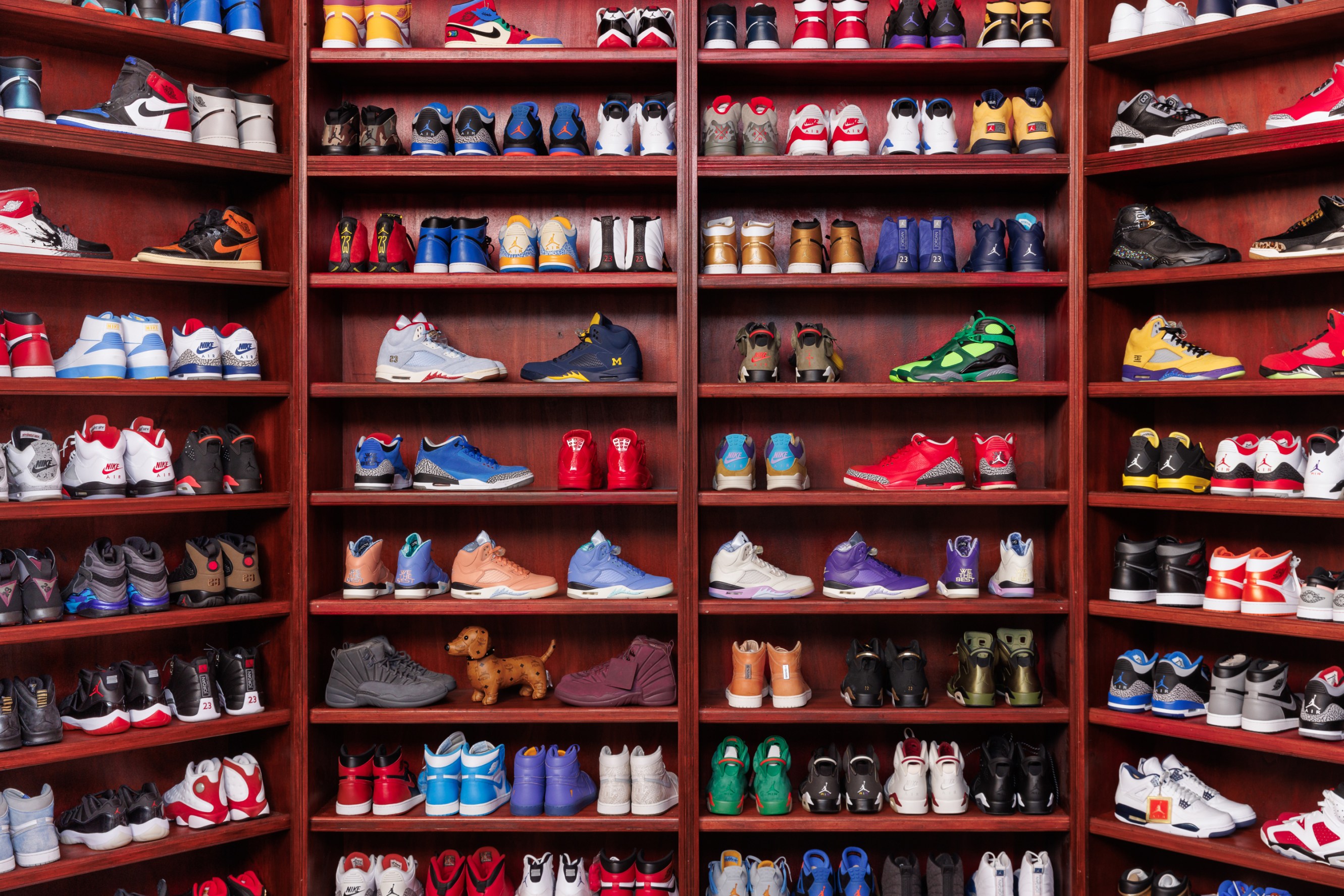 Rows of wooden closet shelves filled with DJ Khaled's shoe collection. 