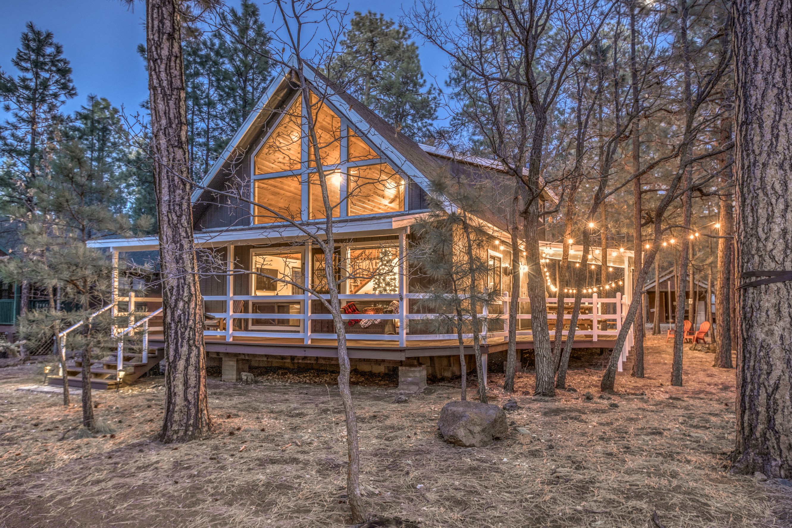 Well-lit cabin in the woods with a wraparound porch