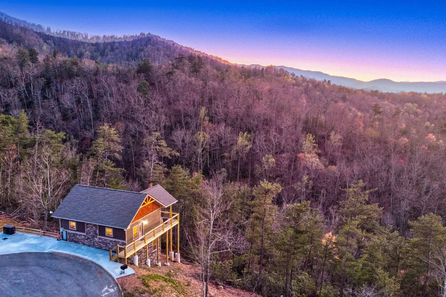 Overhead view of a cabin on the edge of a tree-filled valley